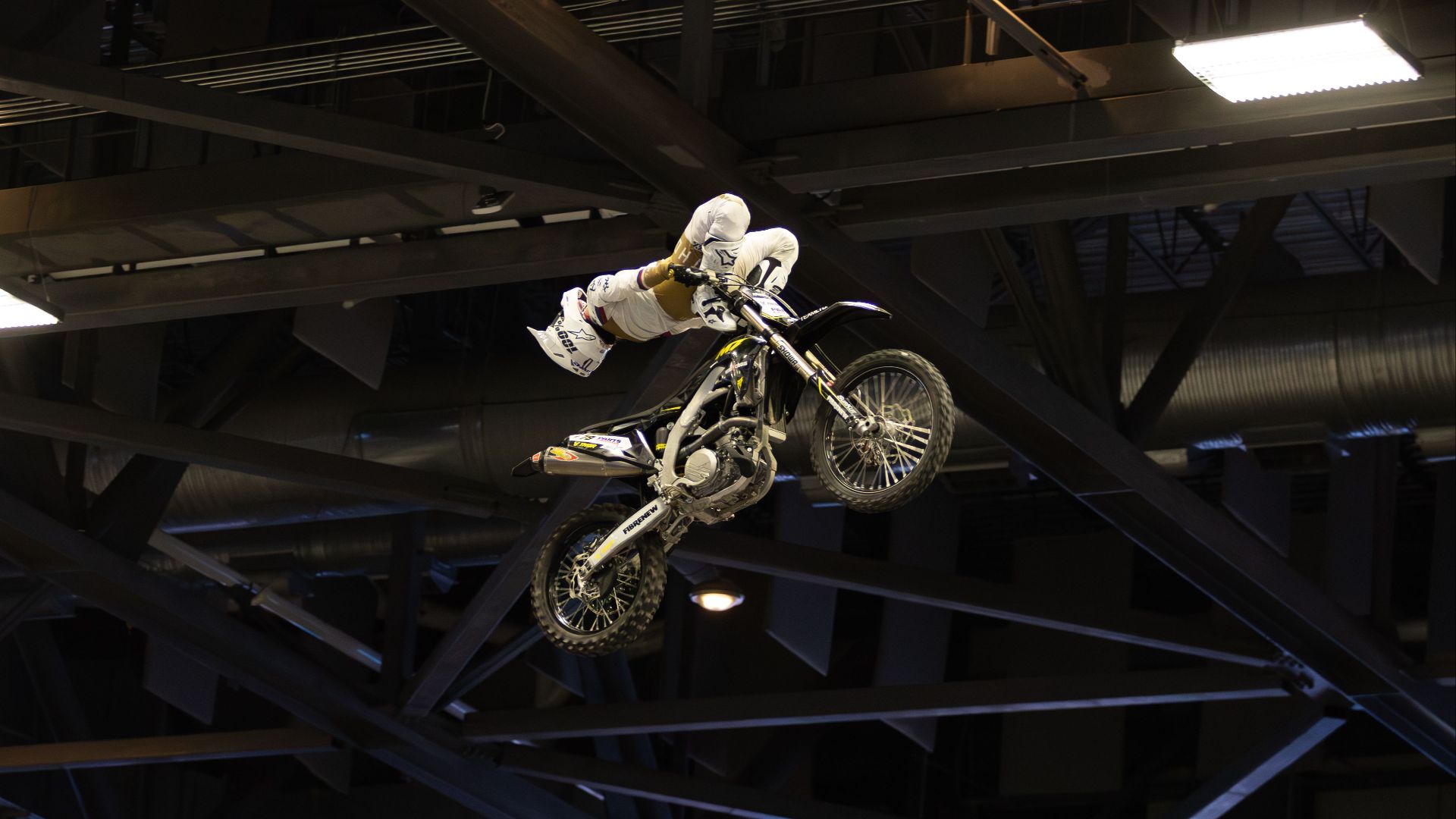 High-angle shot of a motorcyclist performing an indoor freestyle stunt.