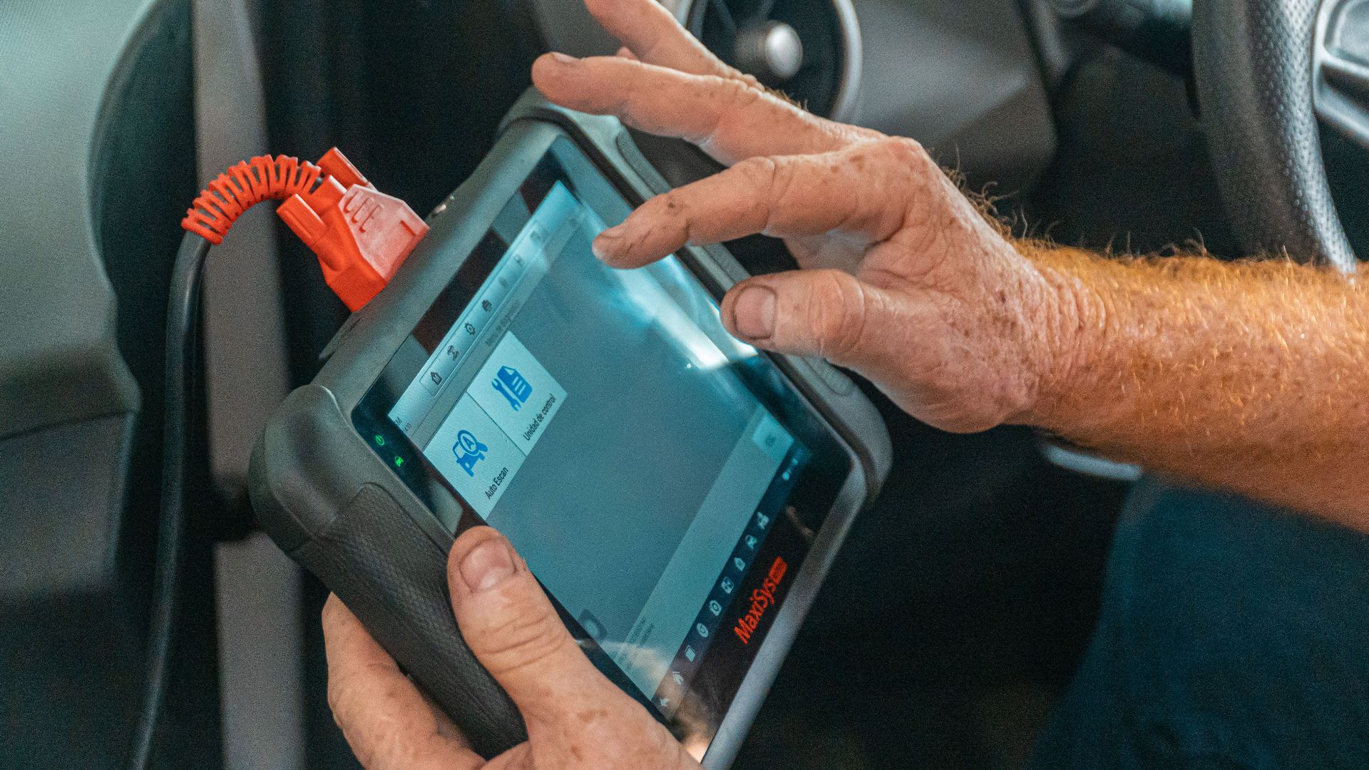Mechanic using a diagnostic tool inside a car to check for engine issues and ensure proper maintenance.