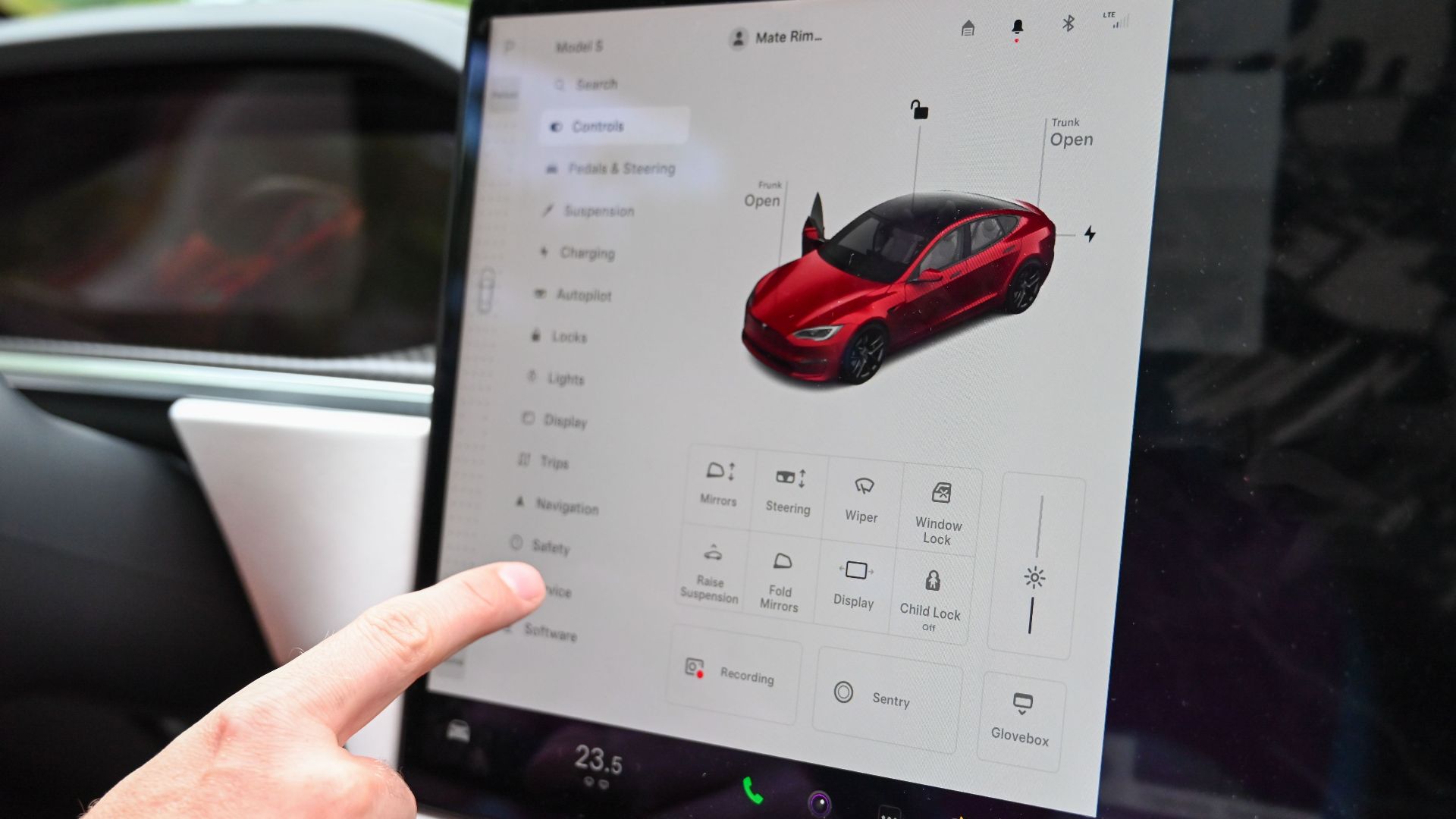 Close-up of a hand interacting with a modern car's touchscreen interface for various controls.