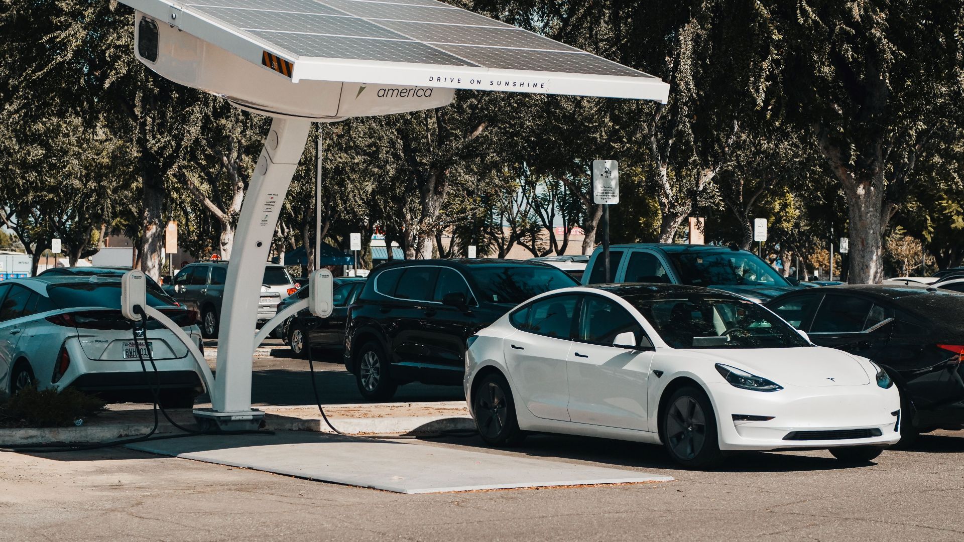 Electric car parked at a solar charging station outdoors, highlighting renewable energy and innovation.