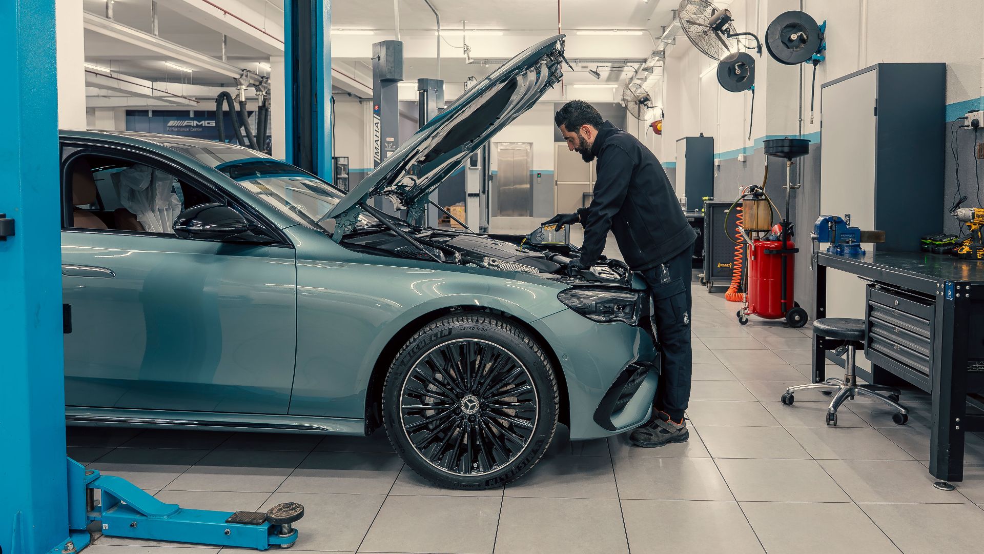 Mechanic inspecting a luxury car inside a well-equipped garage. Vehicle maintenance setting.