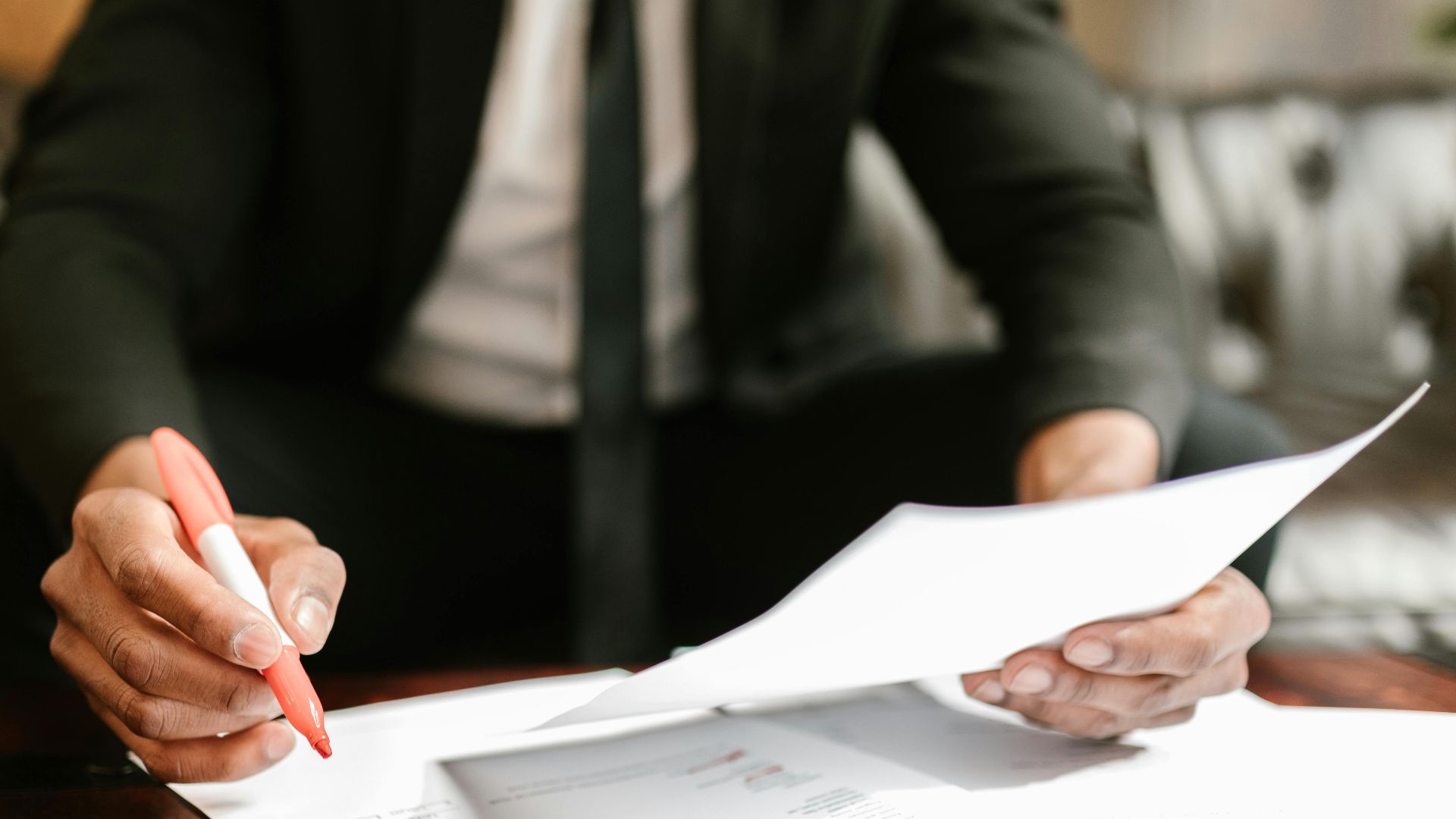 Businessman working with financial documents at office desk, highlighting details.