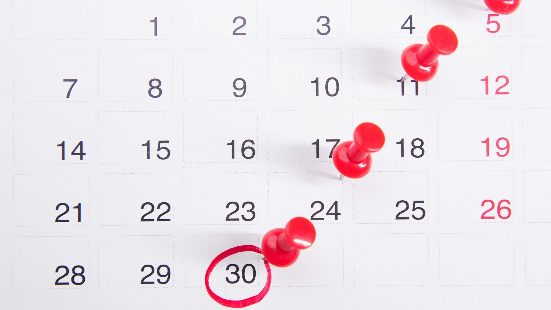 a calendar with red push buttons pinned to it