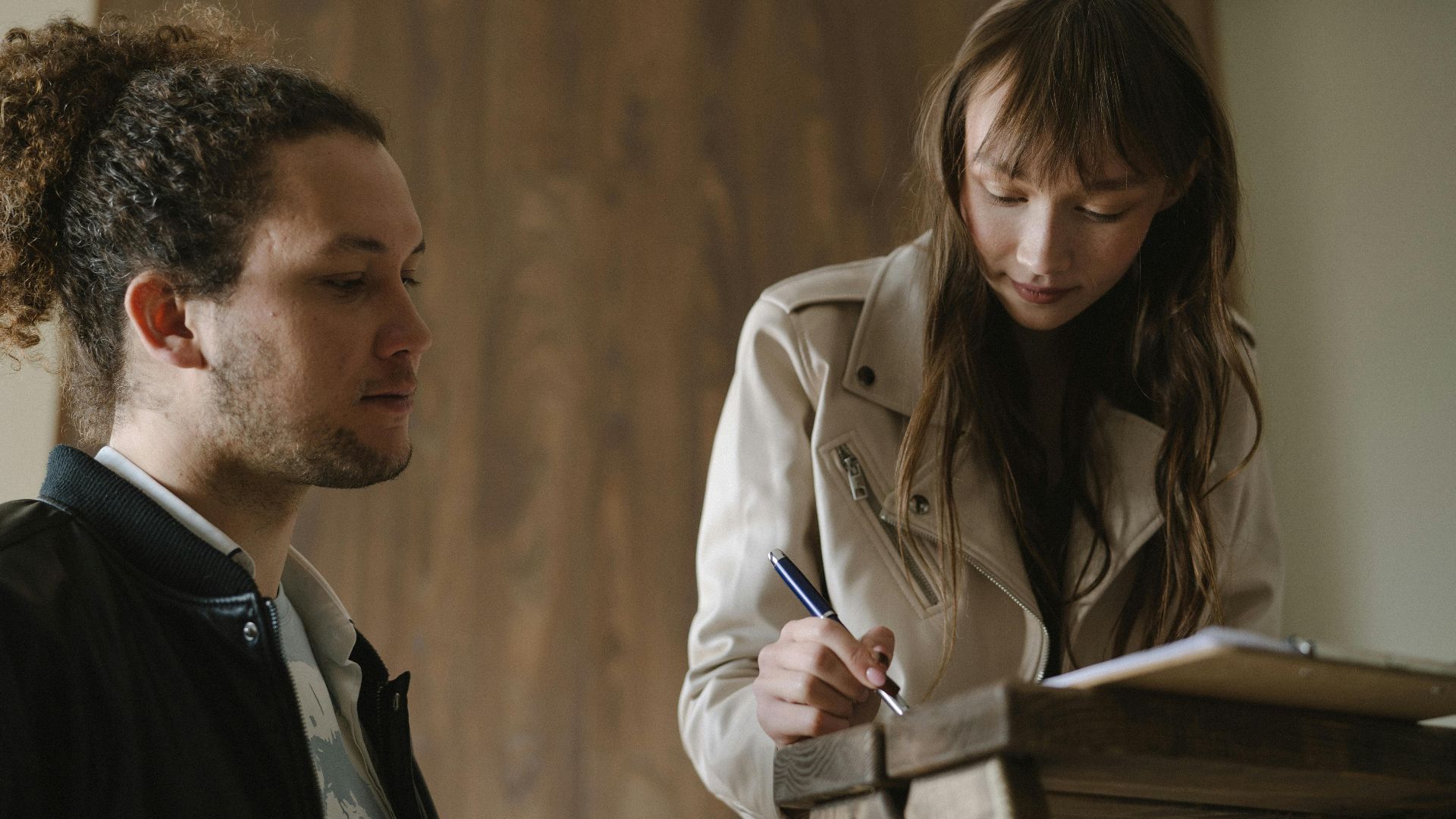A young couple reviews and signs real estate documents indoors.
