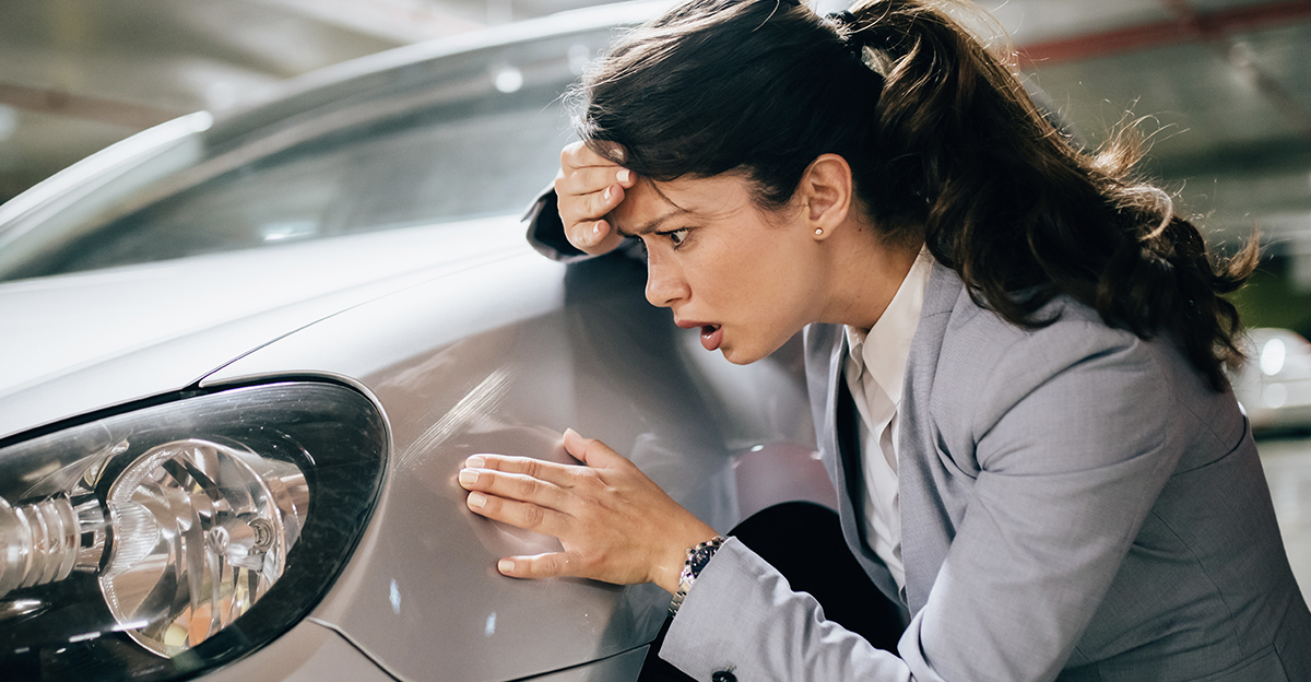 Woman looking at a scratch on her car.
