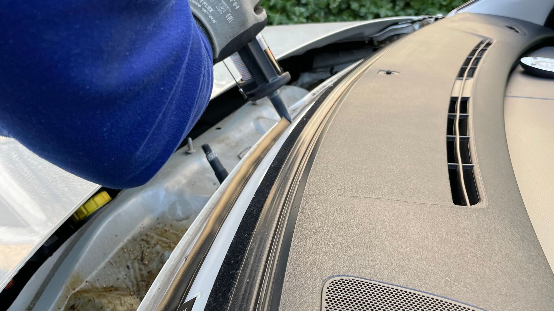 Detailed view of a mechanic repairing a car windshield using glue outdoors in Copenhagen.