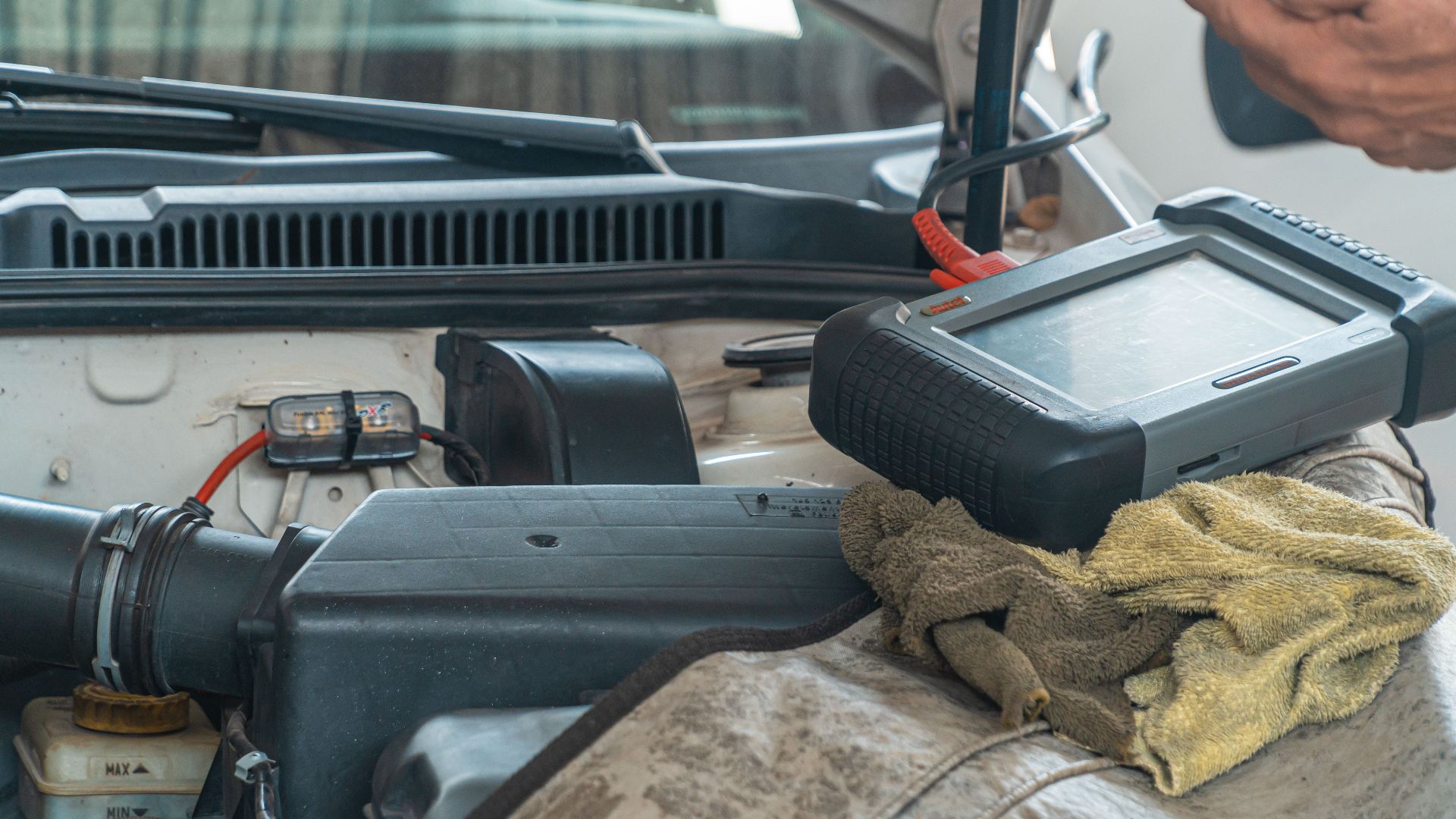 Close-up of a car engine inspection using a diagnostic tool in a garage setting, showcasing automotive maintenance and repair.