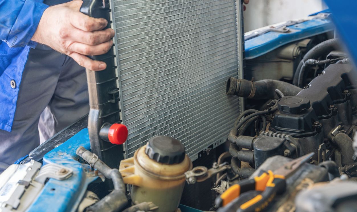 A man installs a new radiator in a car.
