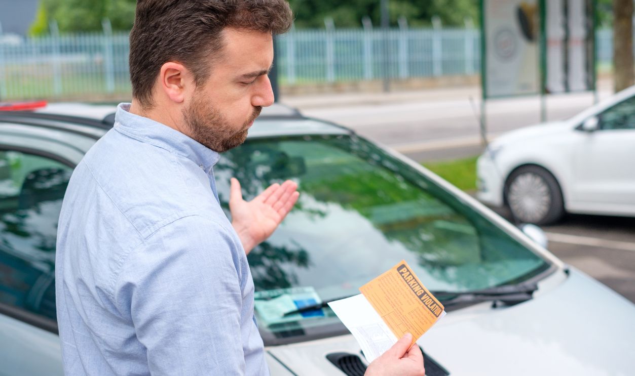 Angry man looking on parking ticket placed under windshield wiper