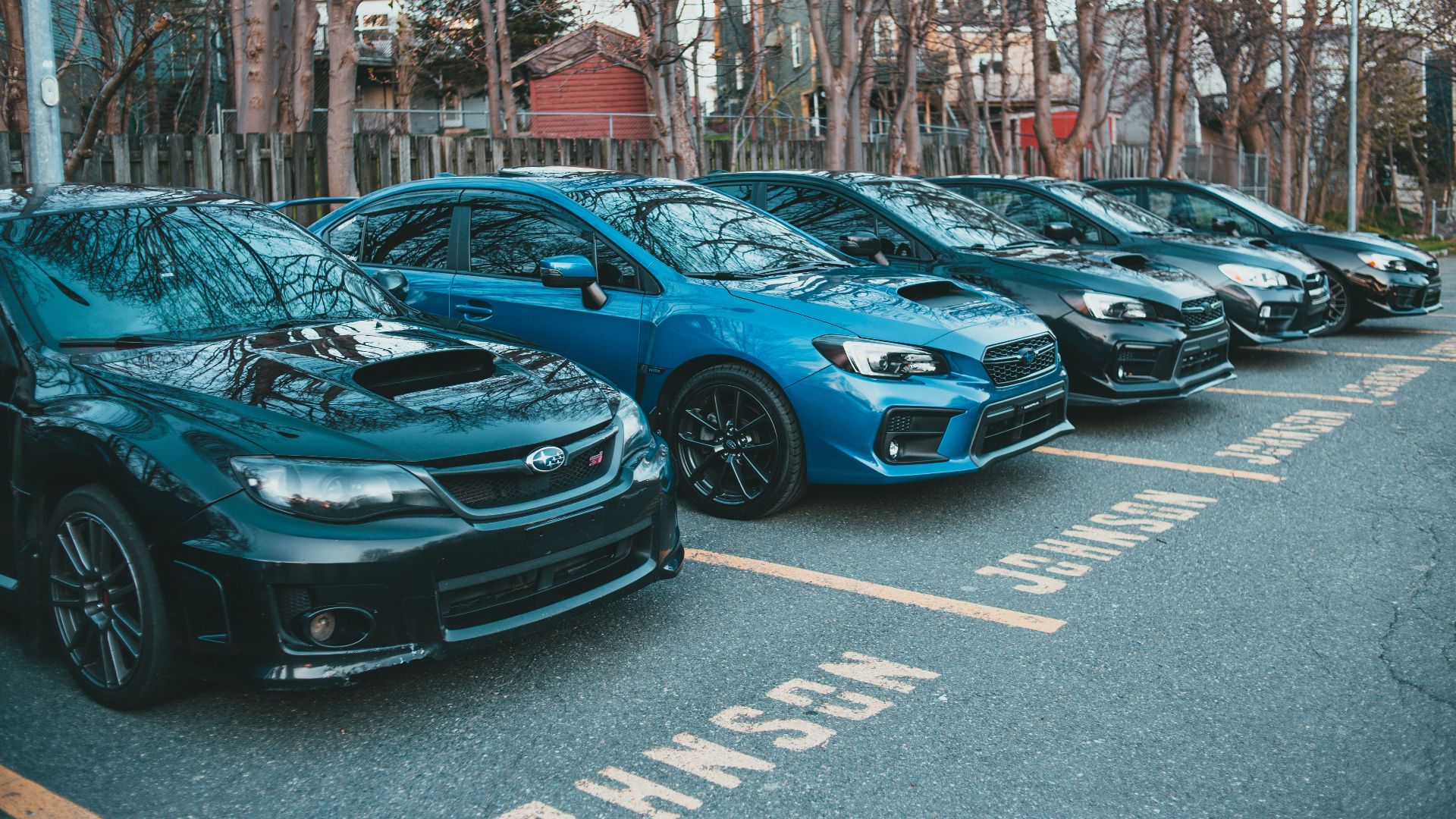 Multiple Subaru cars parked in an outdoor lot lined with trees, showcasing automotive design.