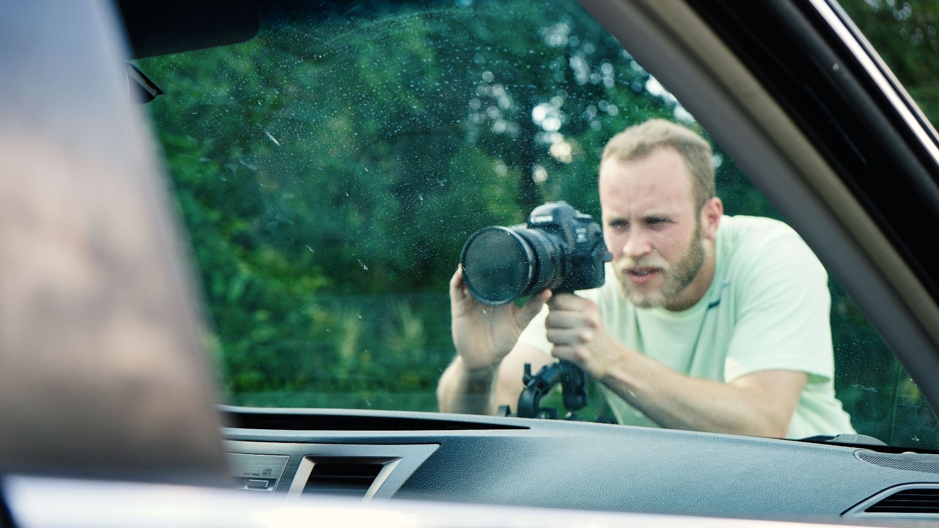 Photographer focusing on details through a car window on a sunny day.