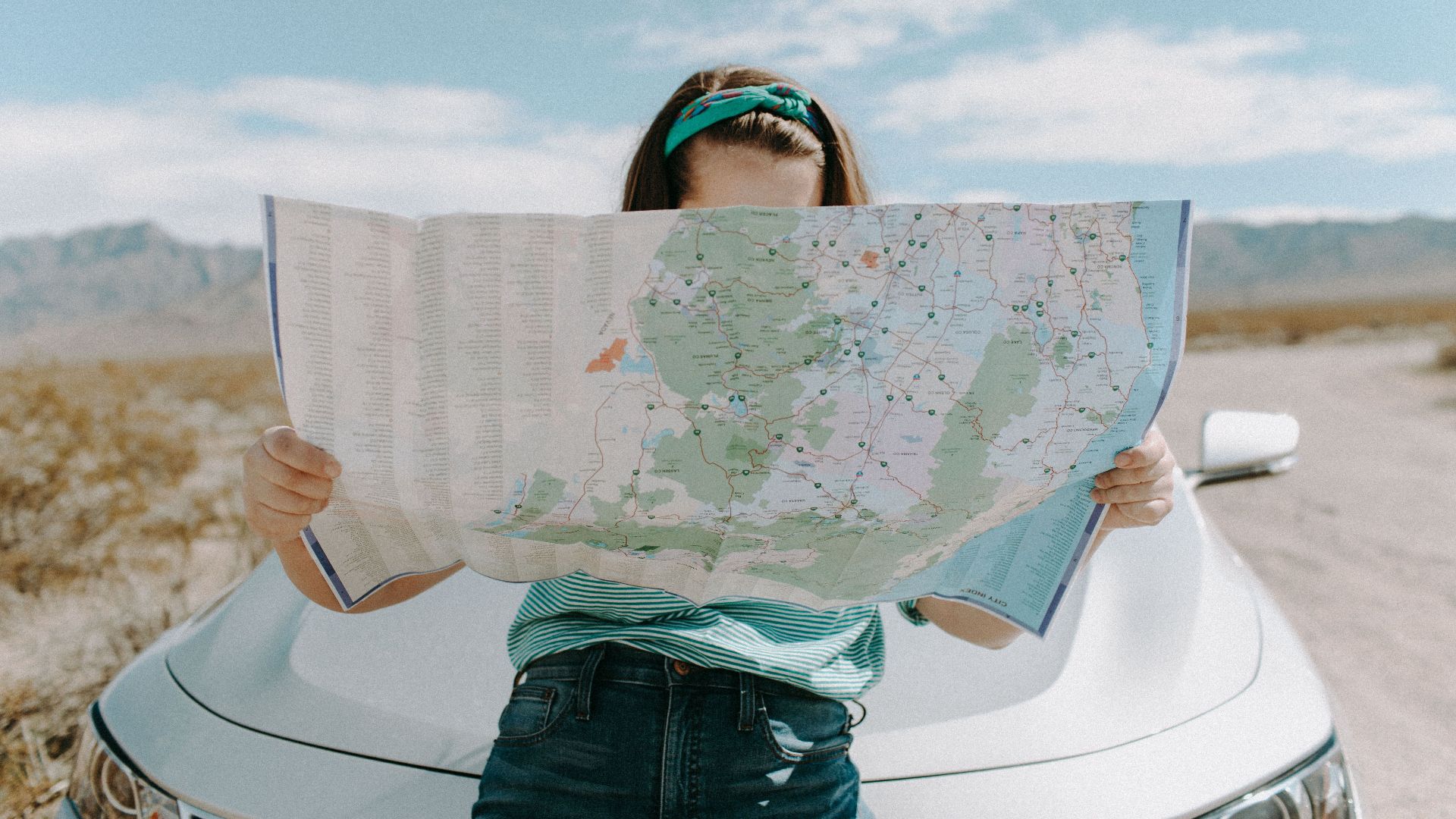 A woman holds a map while traveling through the scenic desert of California, USA.