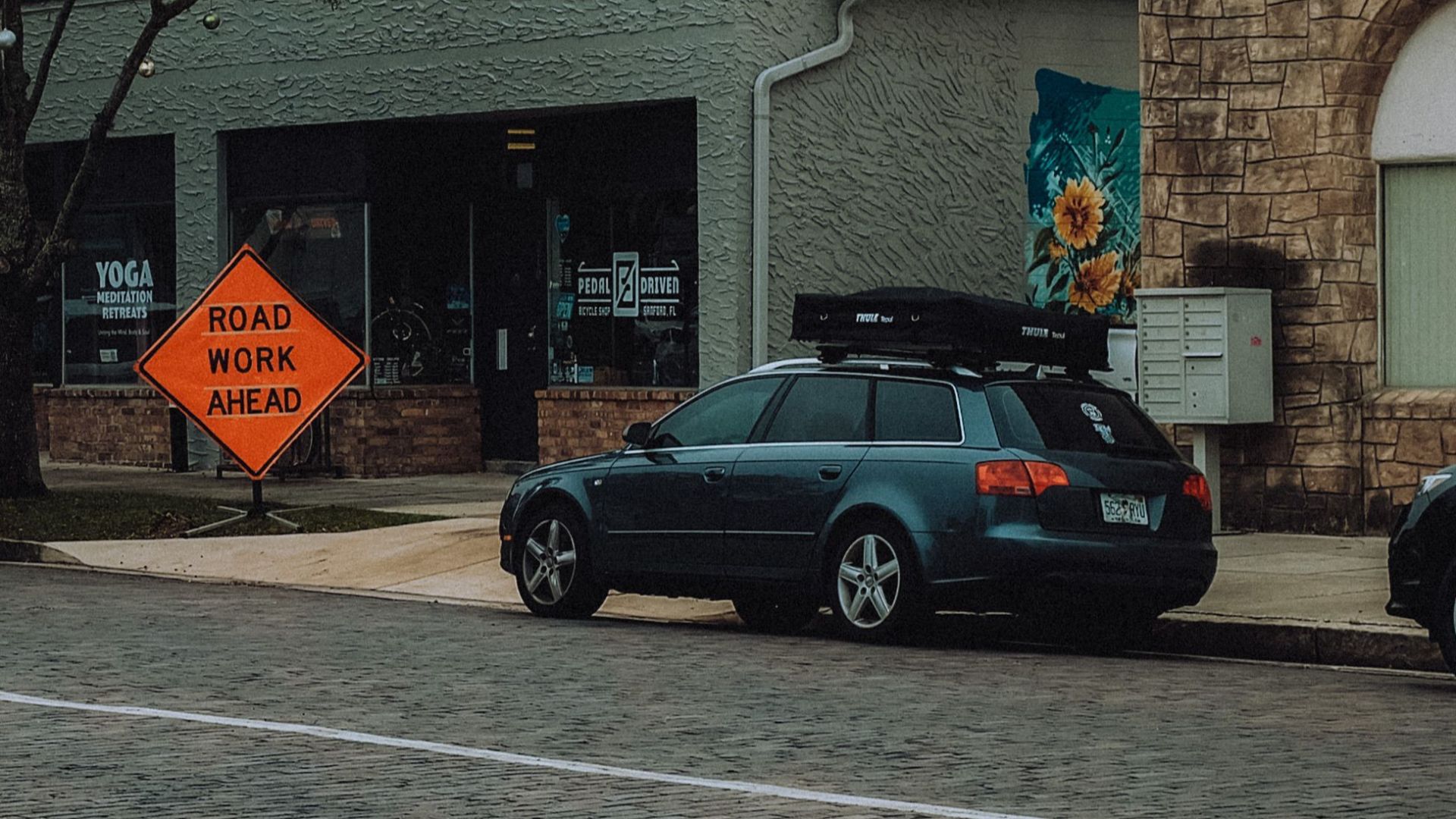A city street scene with parked cars and a road work ahead sign, highlighting urban infrastructure.