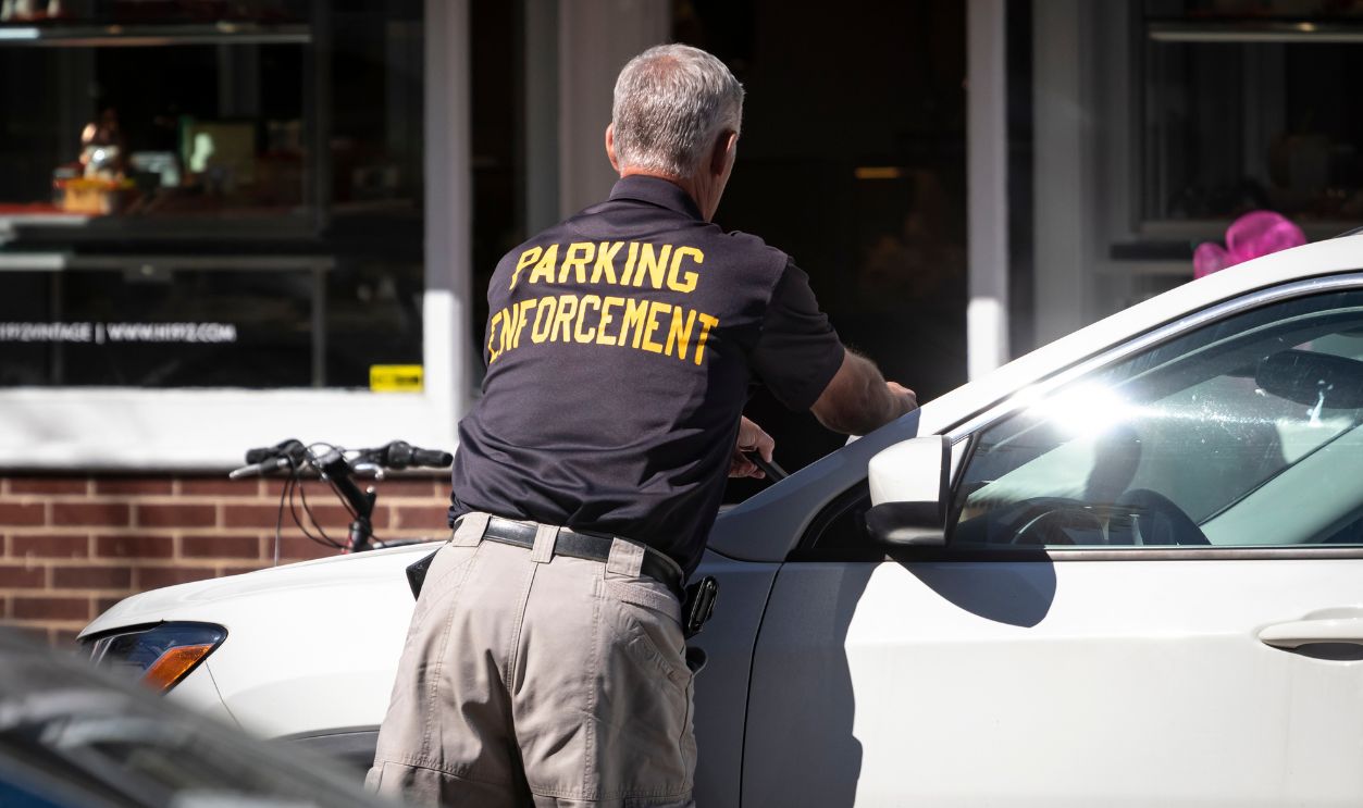 Princeton, NJ - October 4, 2019: Parking Enforcement man places citation ticket on car