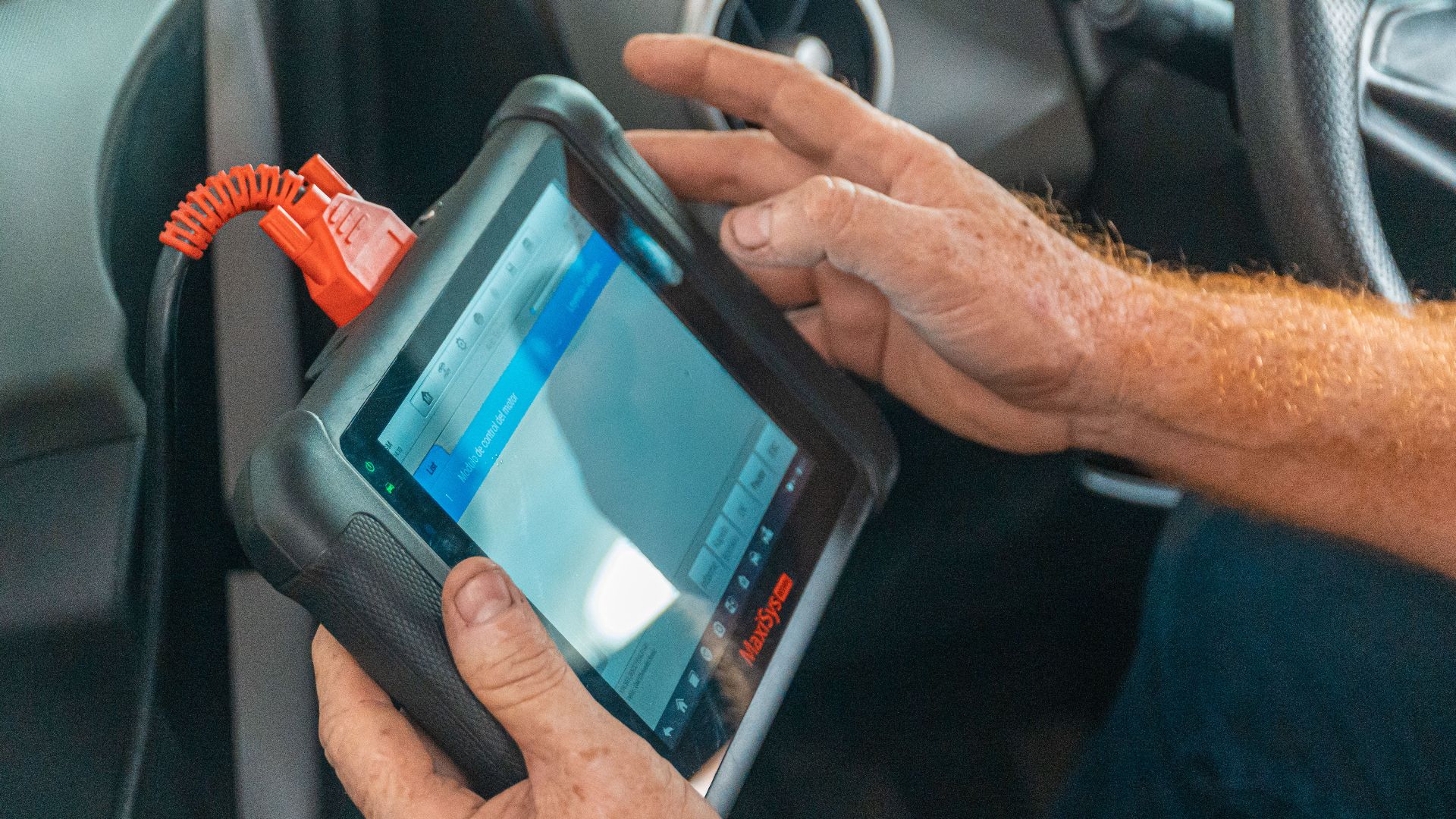 A mechanic uses a diagnostic tablet inside a car for vehicle analysis.