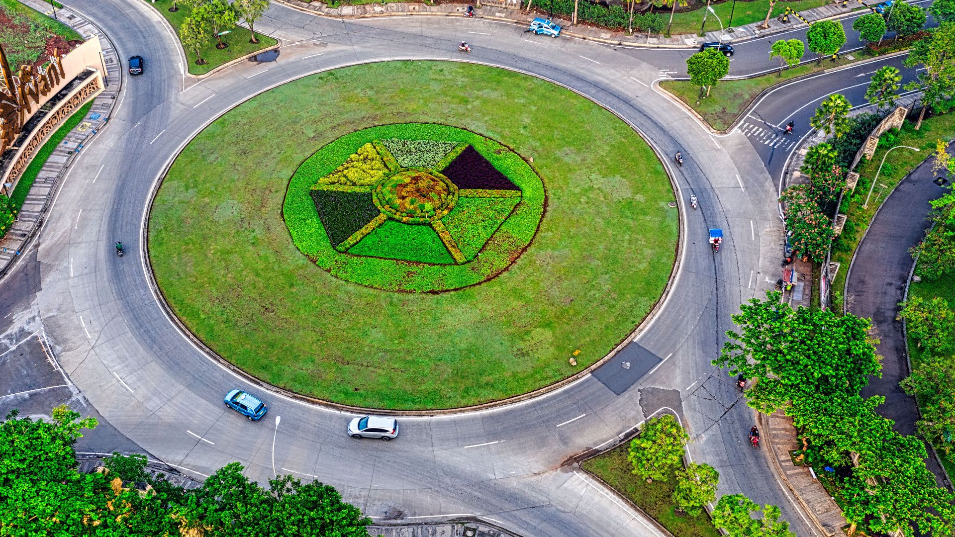 Drone view of contemporary city with modern crossroad and asphalt roads surrounded with green trees and glades