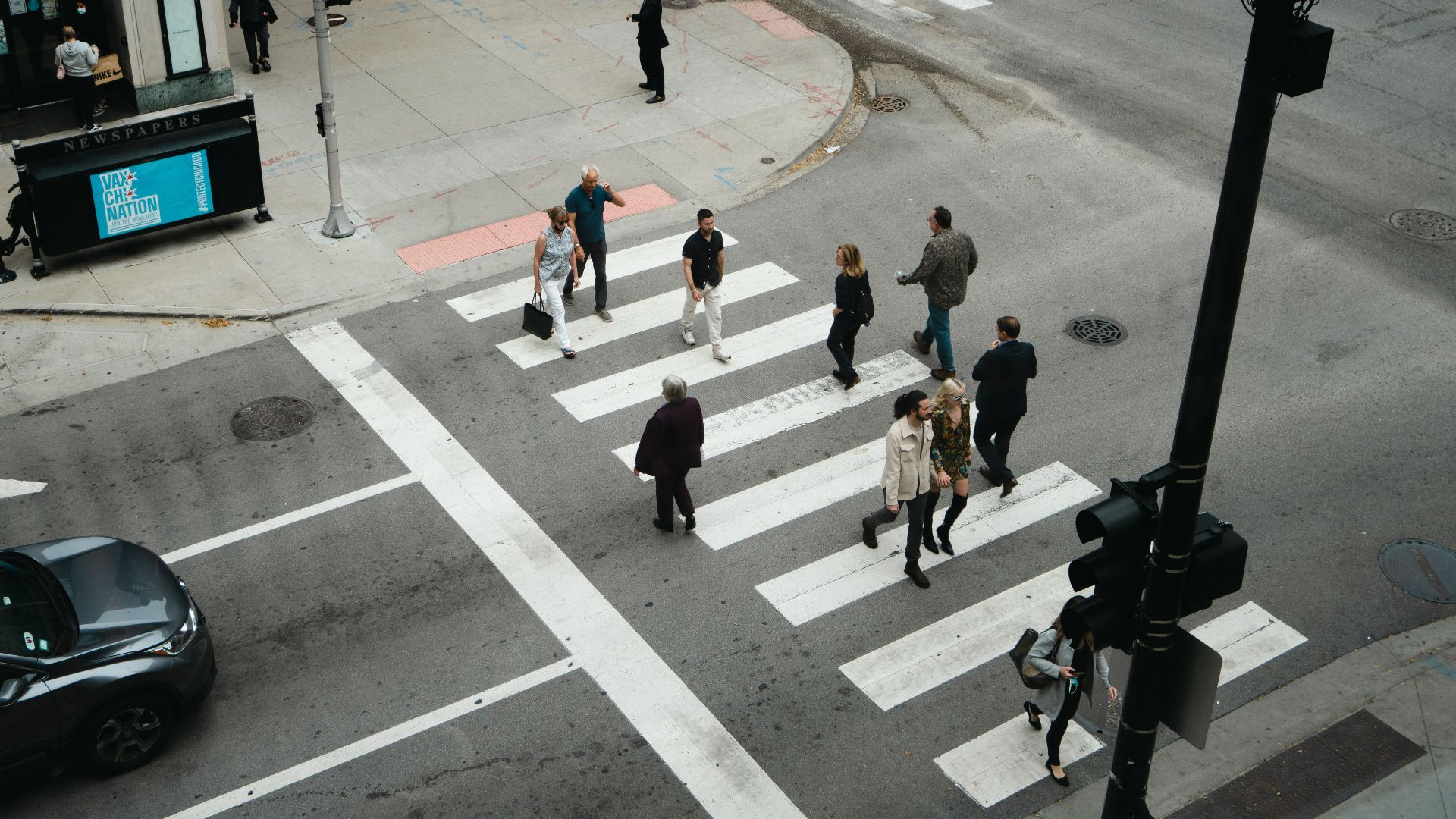 Aerial view of people crossing a city street at a pedestrian crosswalk.