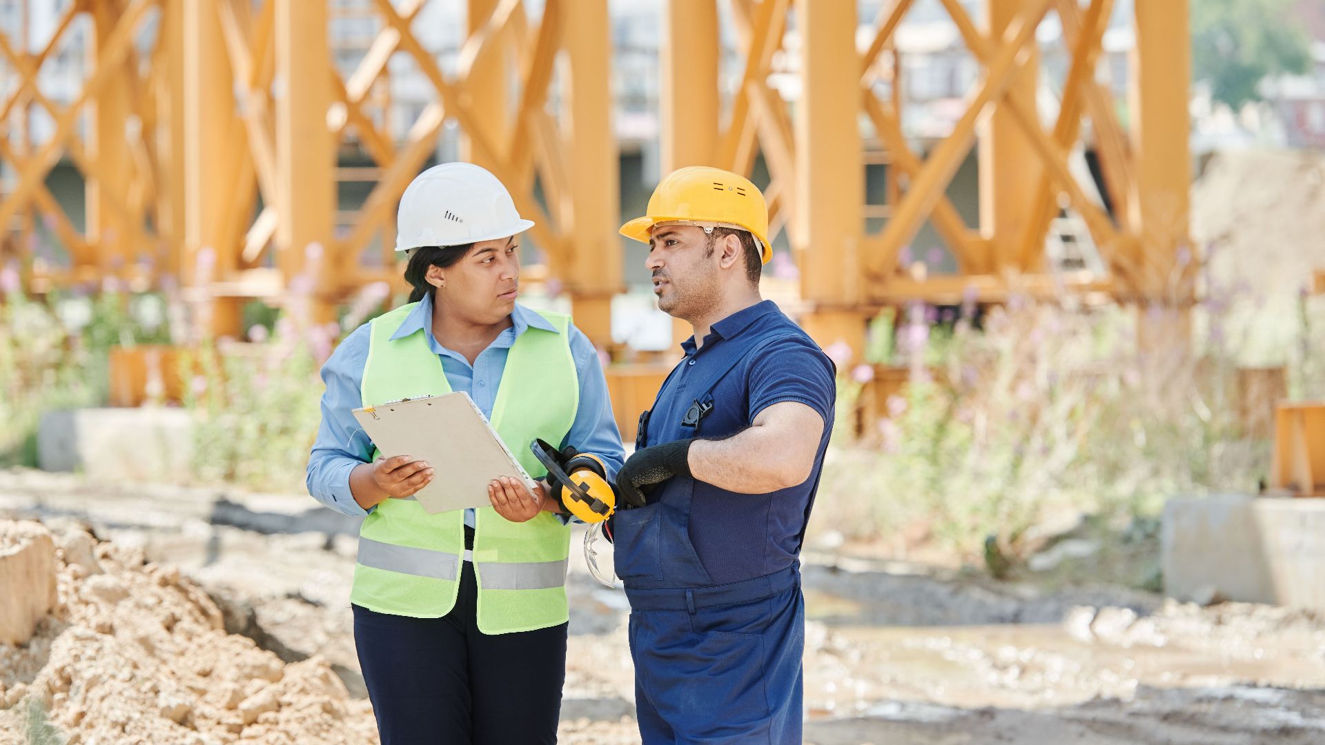 Construction workers engaged in a discussion at a construction site wearing safety gear.