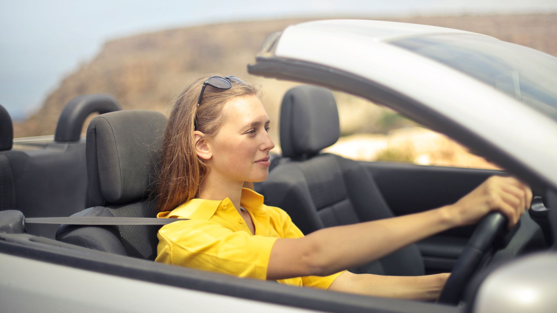 A young woman enjoys driving a convertible on a sunny day in Malta.