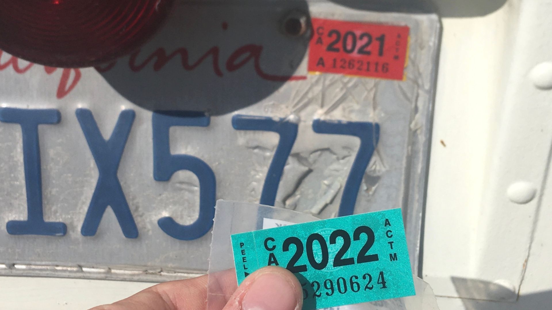 California new 2022 motor vehicle registration sticker (bottom, foreground) about to be applied to the license plate over the previous 2021 sticker (top, background)