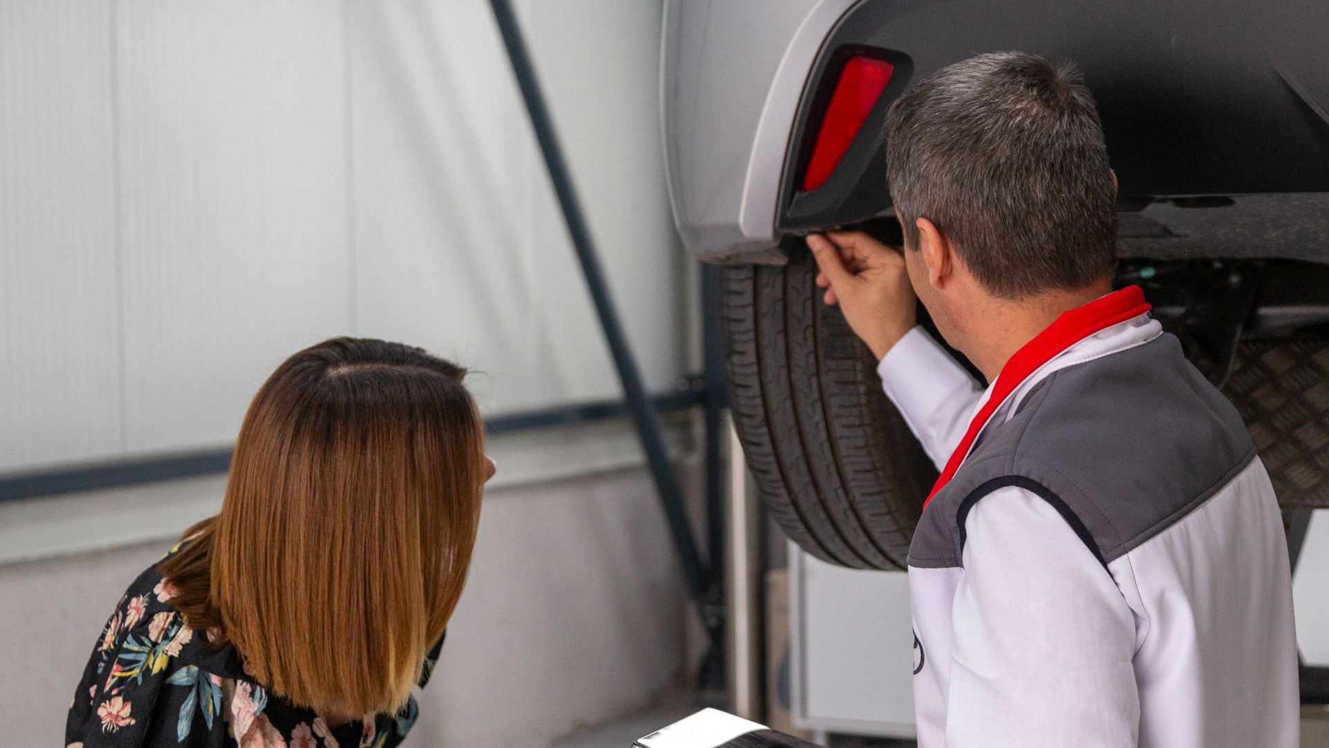 A man and a woman looking under a car
