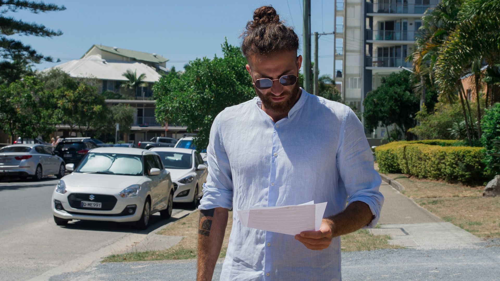 man in white button up t-shirt holding white printer paper
