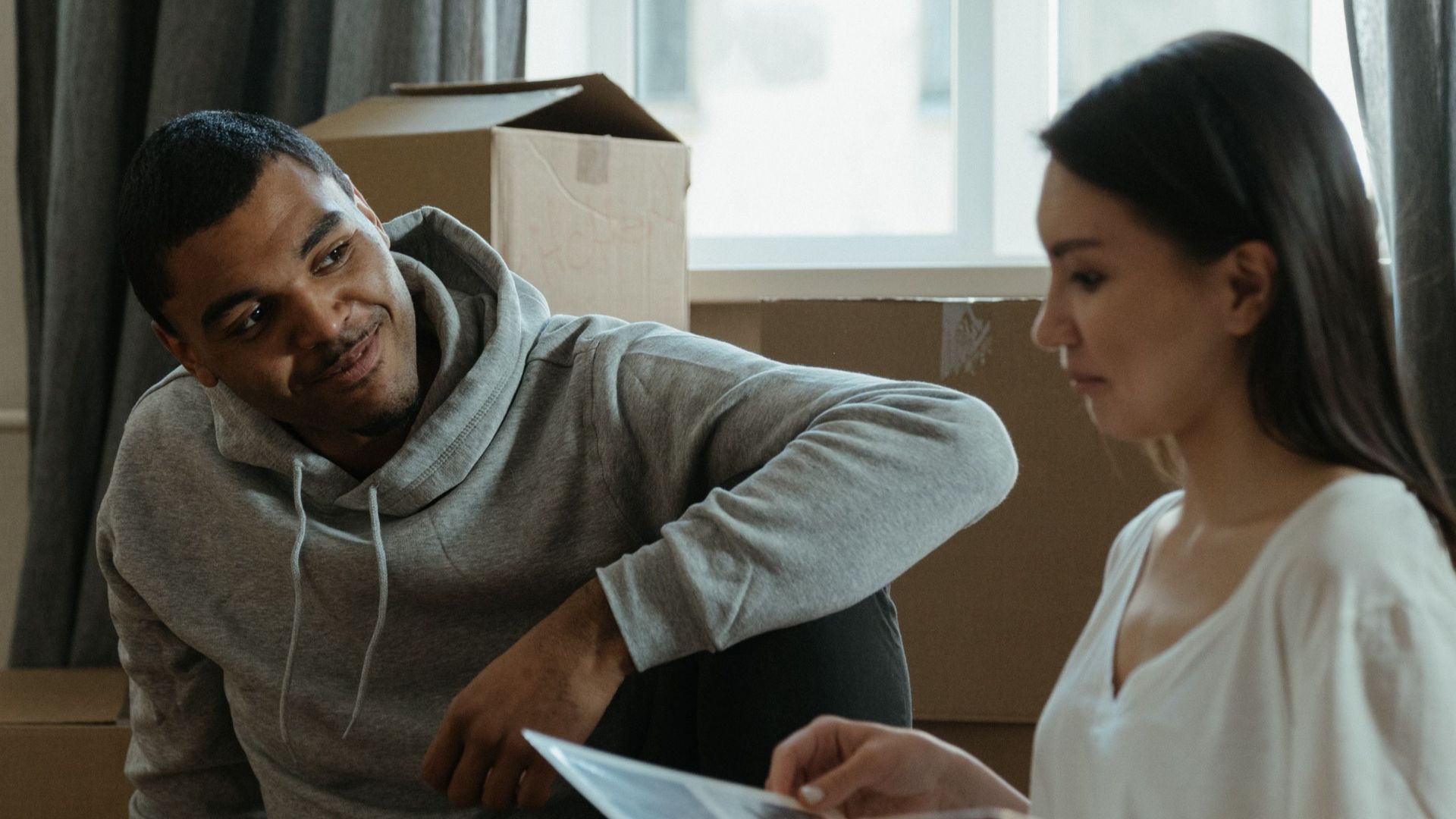 A couple exploring their new home while unpacking boxes and looking at a photo album.