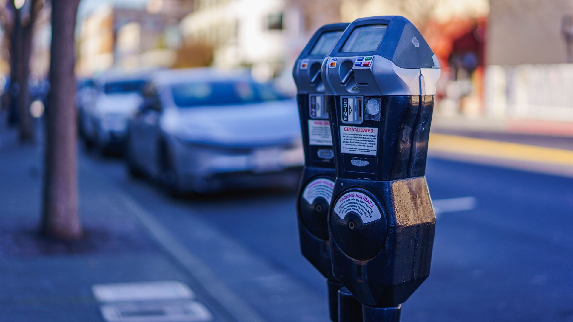 Close-up of parking meters in a bustling city street during the day, showcasing urban infrastructure.