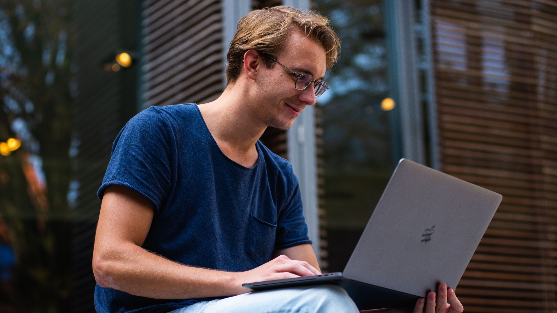 A young man sitting outdoors in Leiden, Netherlands, working on a laptop.