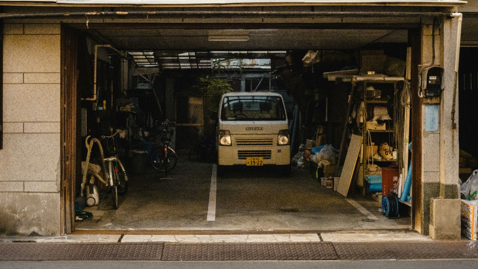 Small white van parked inside a garage workshop entrance