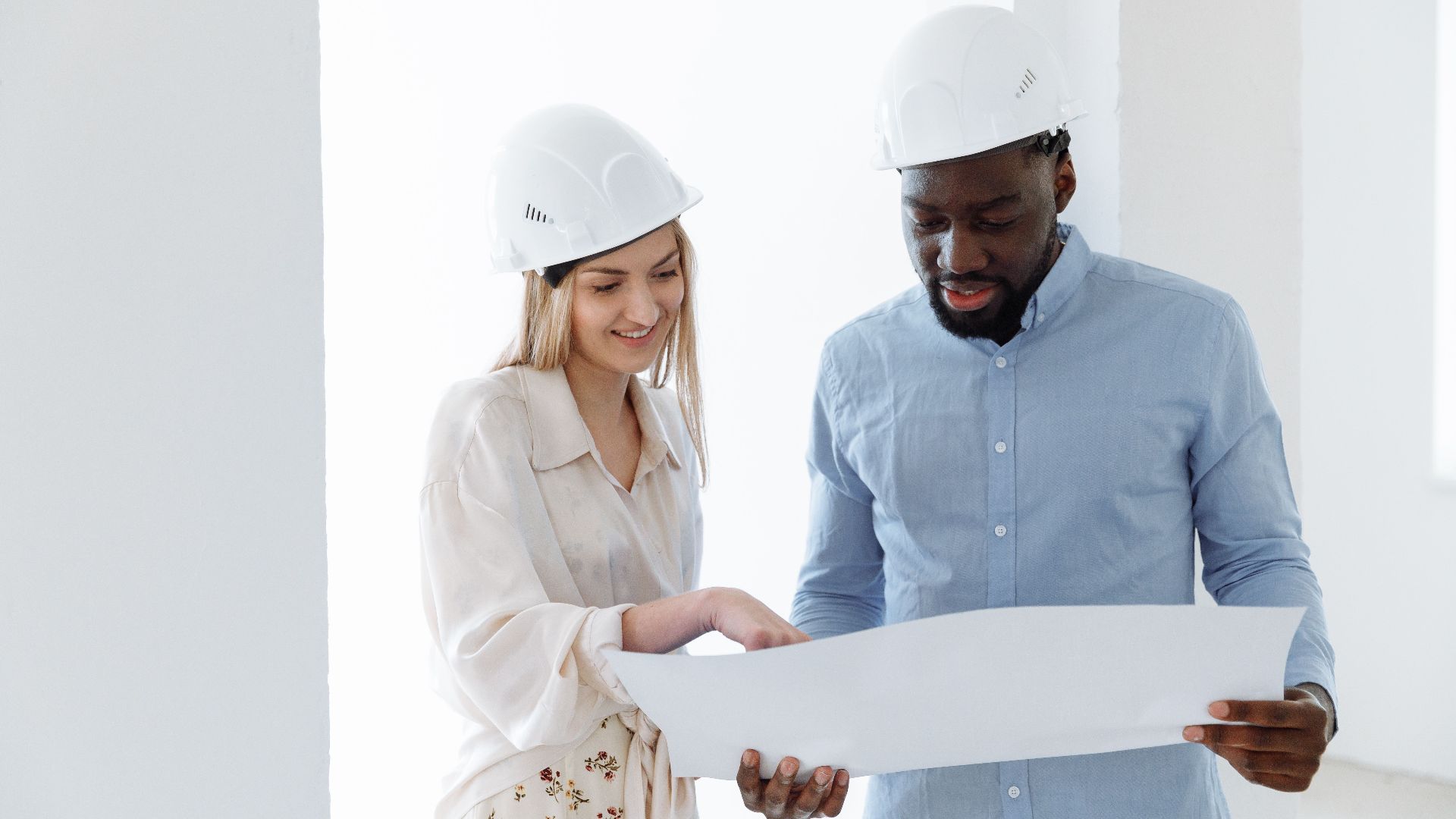 Two architects discussing a project with blueprints indoors.