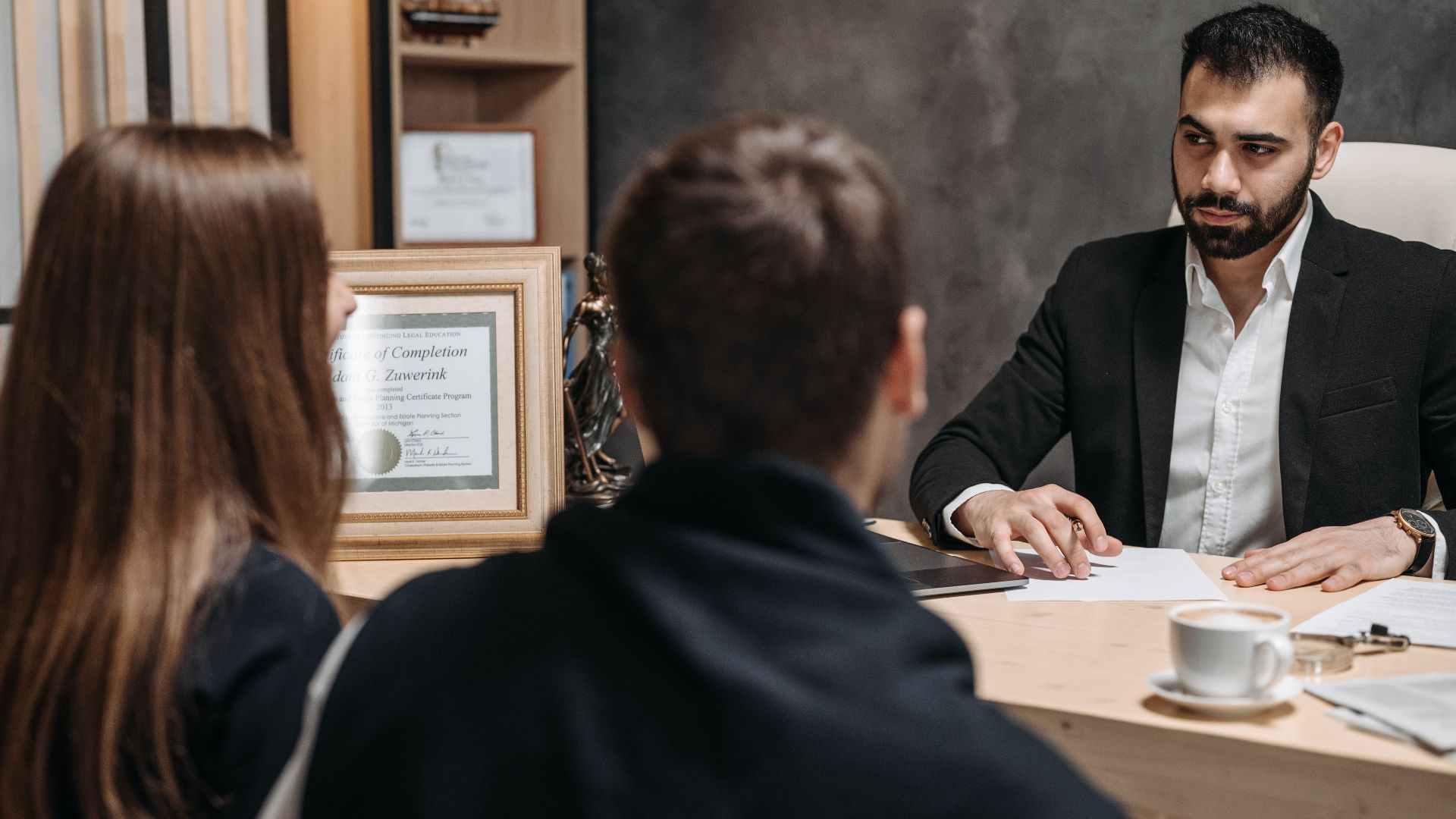 A lawyer in an elegant office meeting with clients, discussing documents.