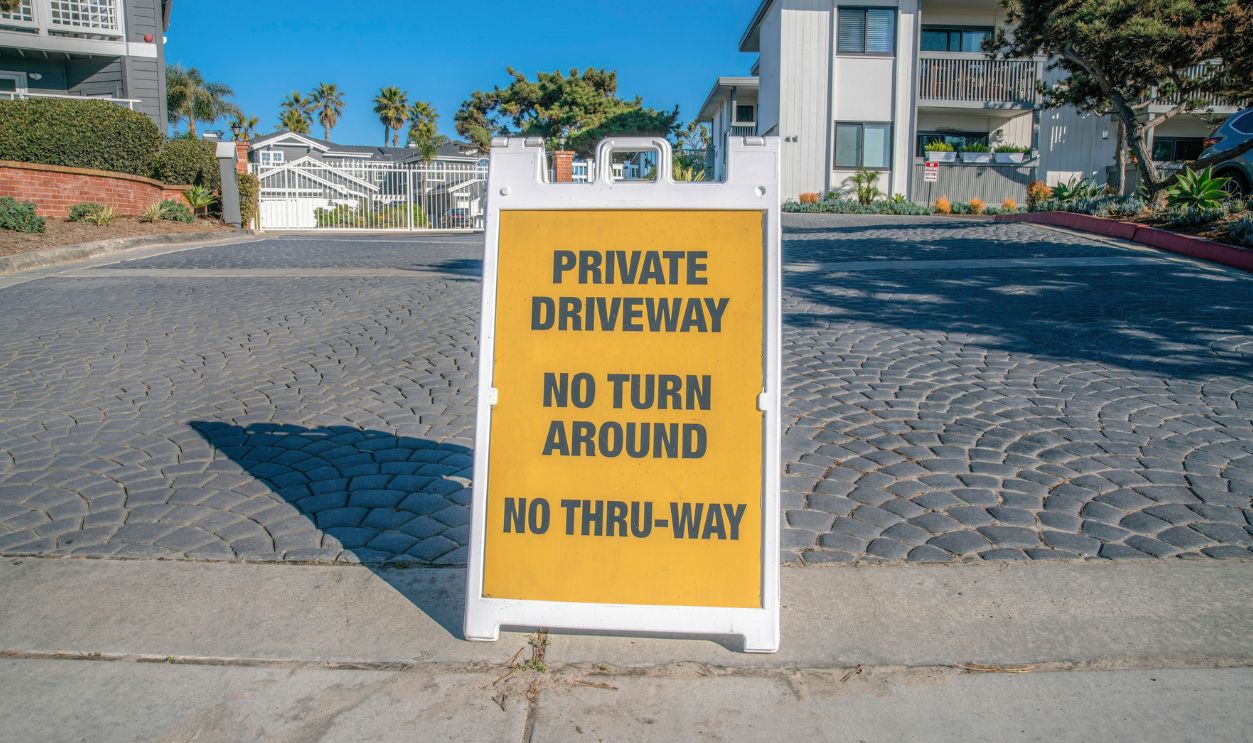 La Jolla, California- Signage with Private Driveway, No Turn Around, and No Thru-Way. Signage at the front of a driveway with stone pavement and gated residential community at the back.