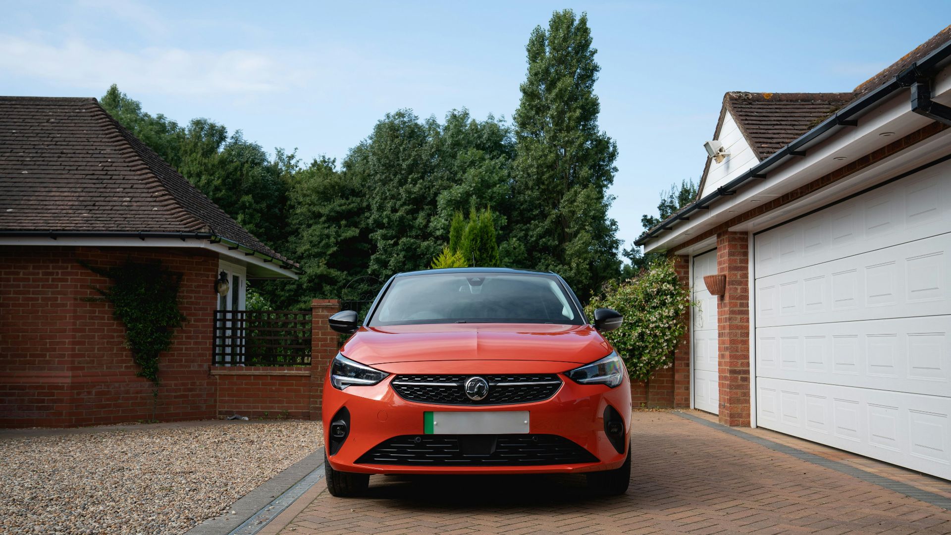Orange car parked in driveway between garages.