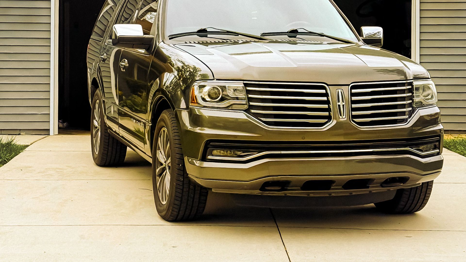 A sleek luxury SUV parked in front of a residential garage on a driveway.
