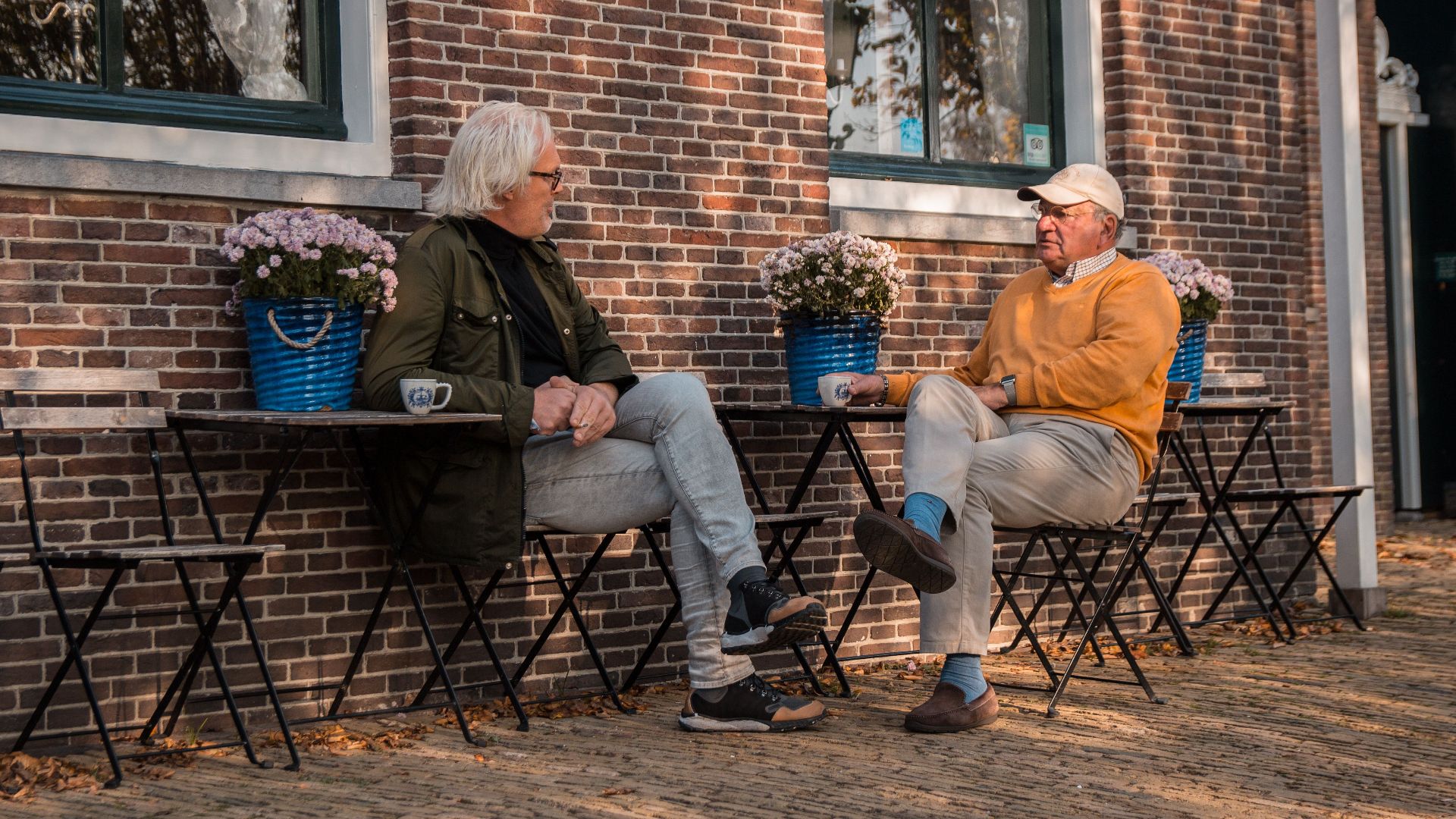 Elderly men enjoying coffee and conversation outside a cafe in Amsterdam.