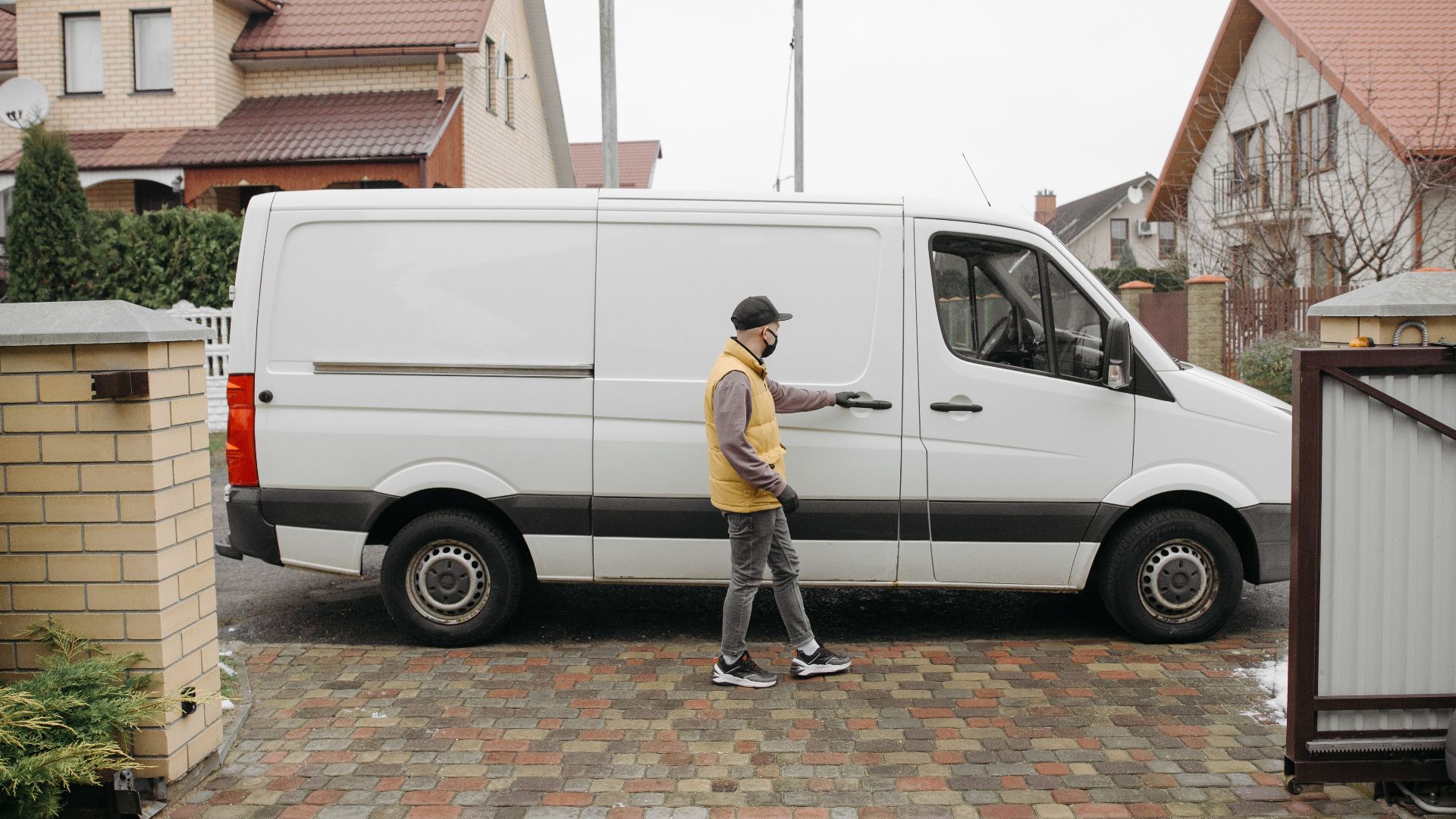 A delivery man exits his van in a suburban residential neighborhood for home delivery.