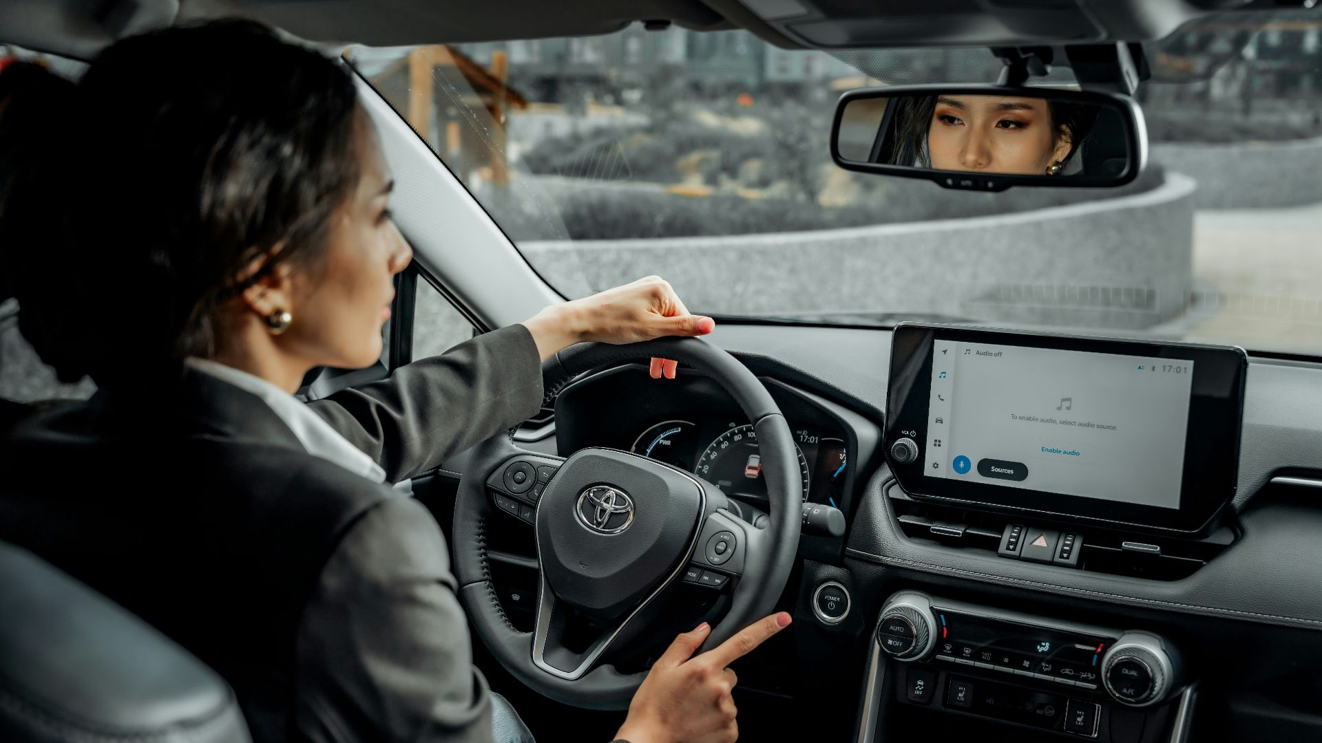 A woman driving a car with a man in the back seat