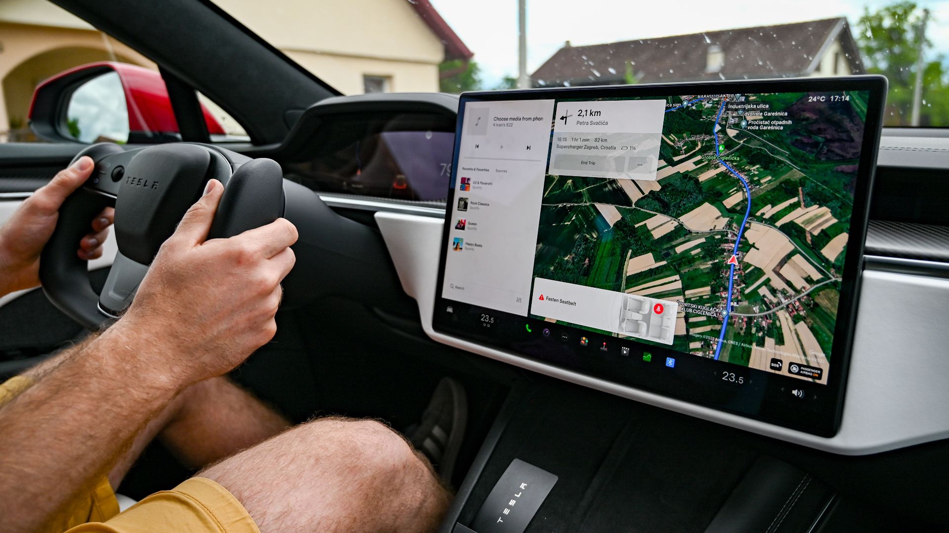 Man driving Tesla using GPS on touchscreen dashboard for navigation.