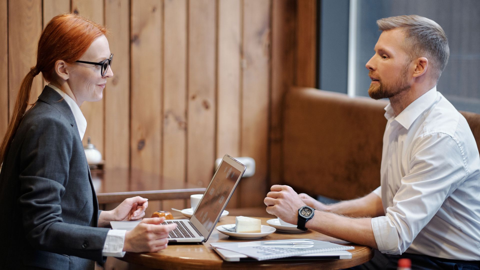 Two business professionals discuss work over coffee in a cozy cafe.