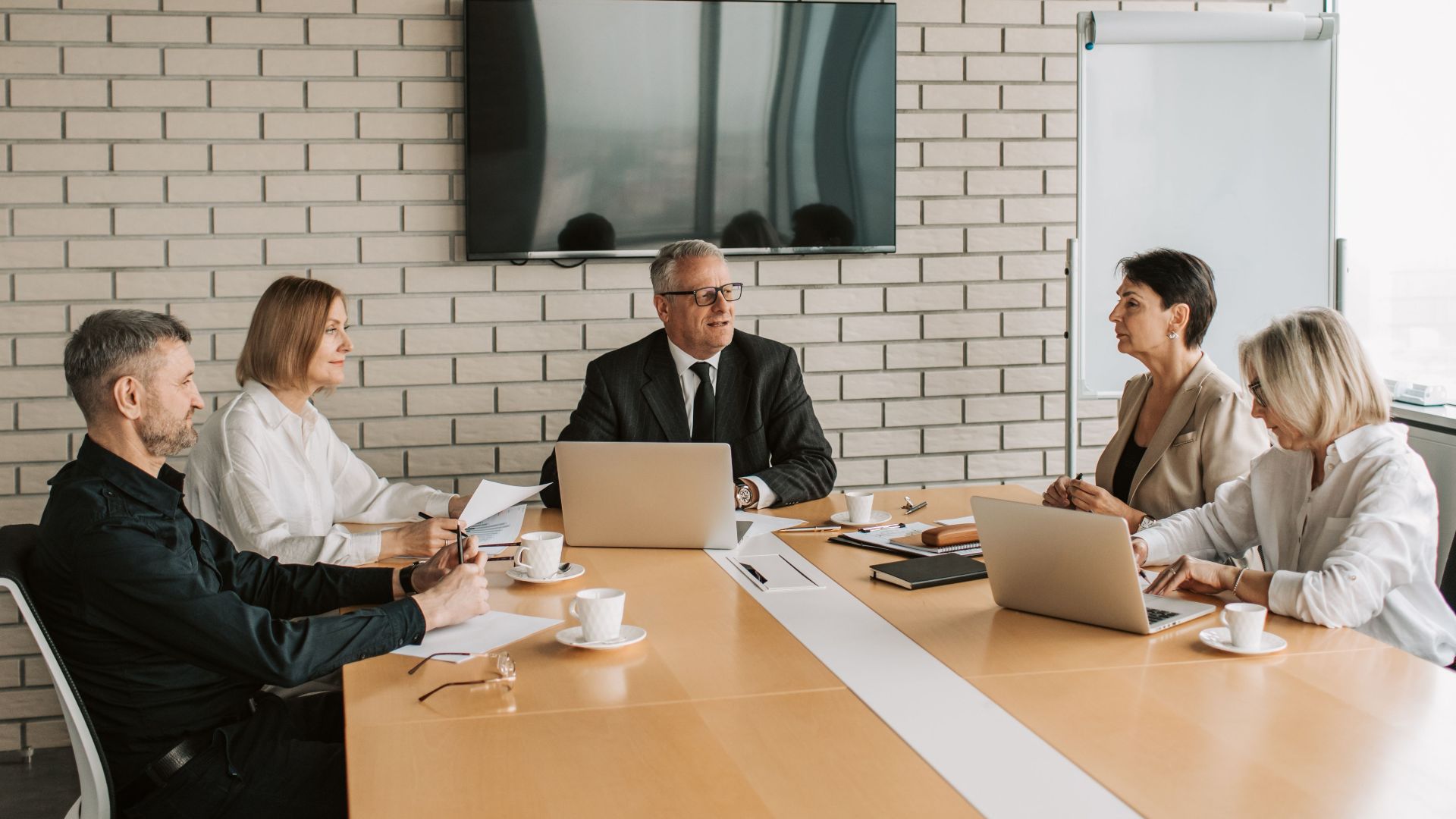 A professional team meeting with laptops and documents in a modern office.