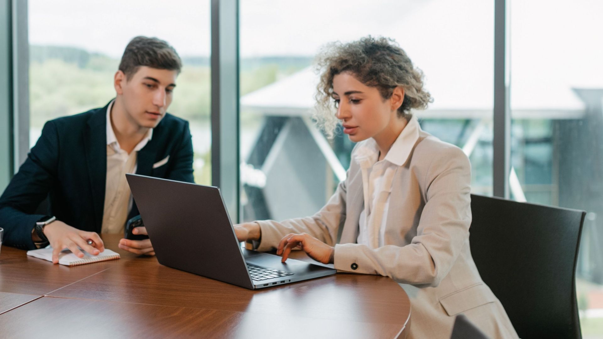 Two colleagues engaged in a business meeting in a well-lit modern office space.