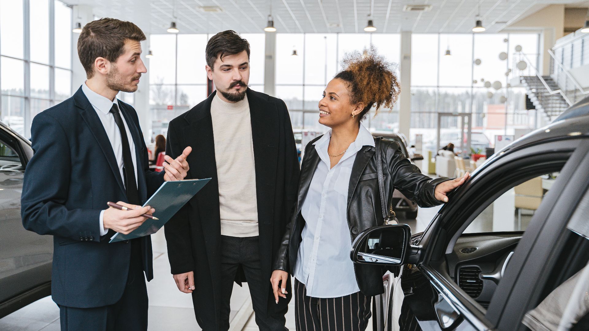 A diverse team of adults discussing a car purchase in a dealership showroom.