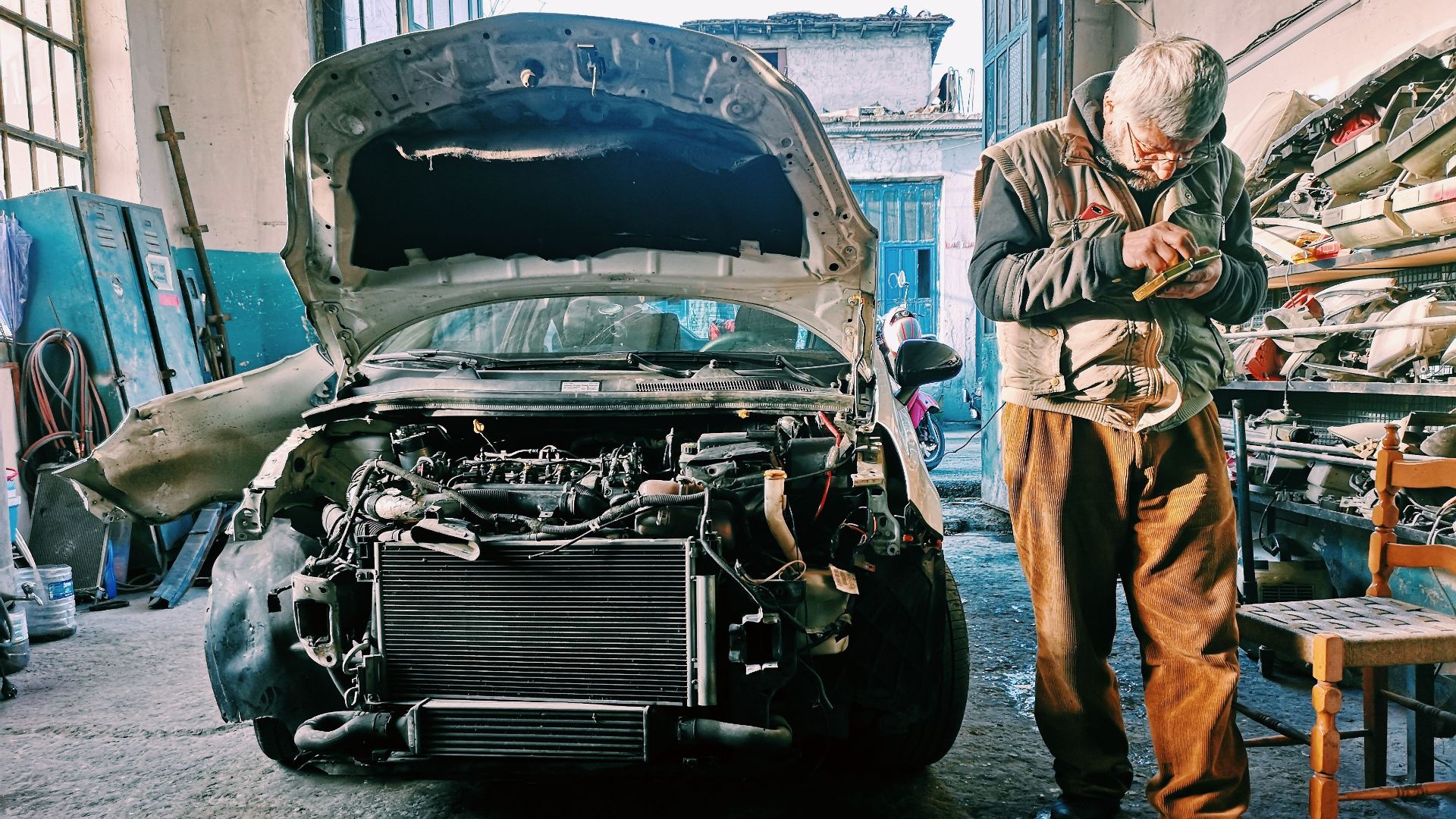Mechanic repairing car in an auto workshop with the hood open showcasing the engine.