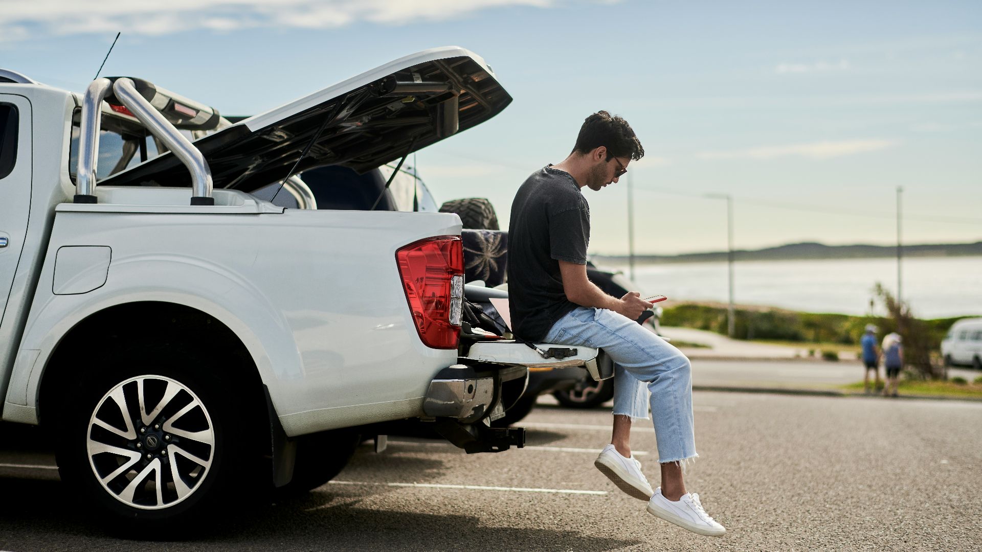 man sitting on car looking at phone