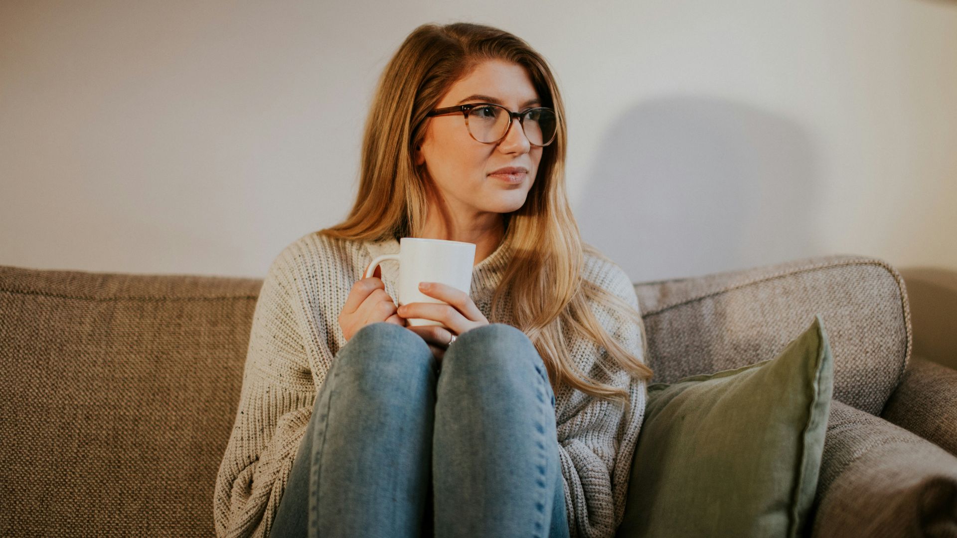 woman in blue denim jeans sitting on gray sofa