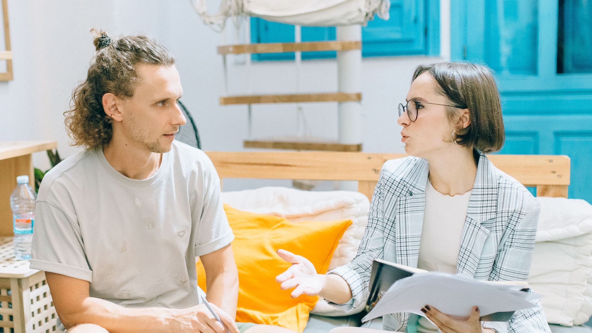 A man and woman discussing work in a stylish, bright living room setting.