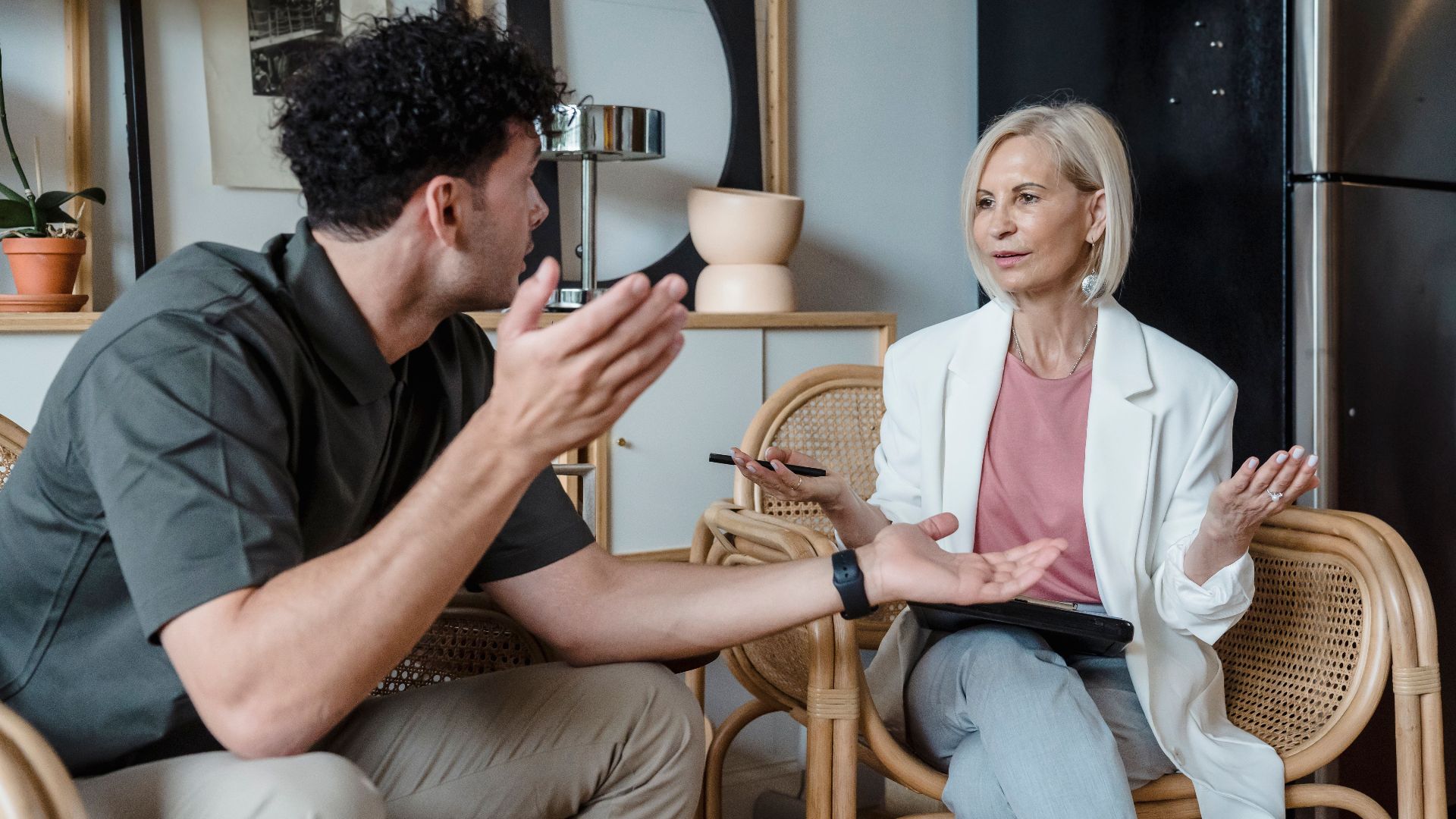 Two adults engaged in a lively discussion in a stylish indoor setting, illustrating communication and connection.