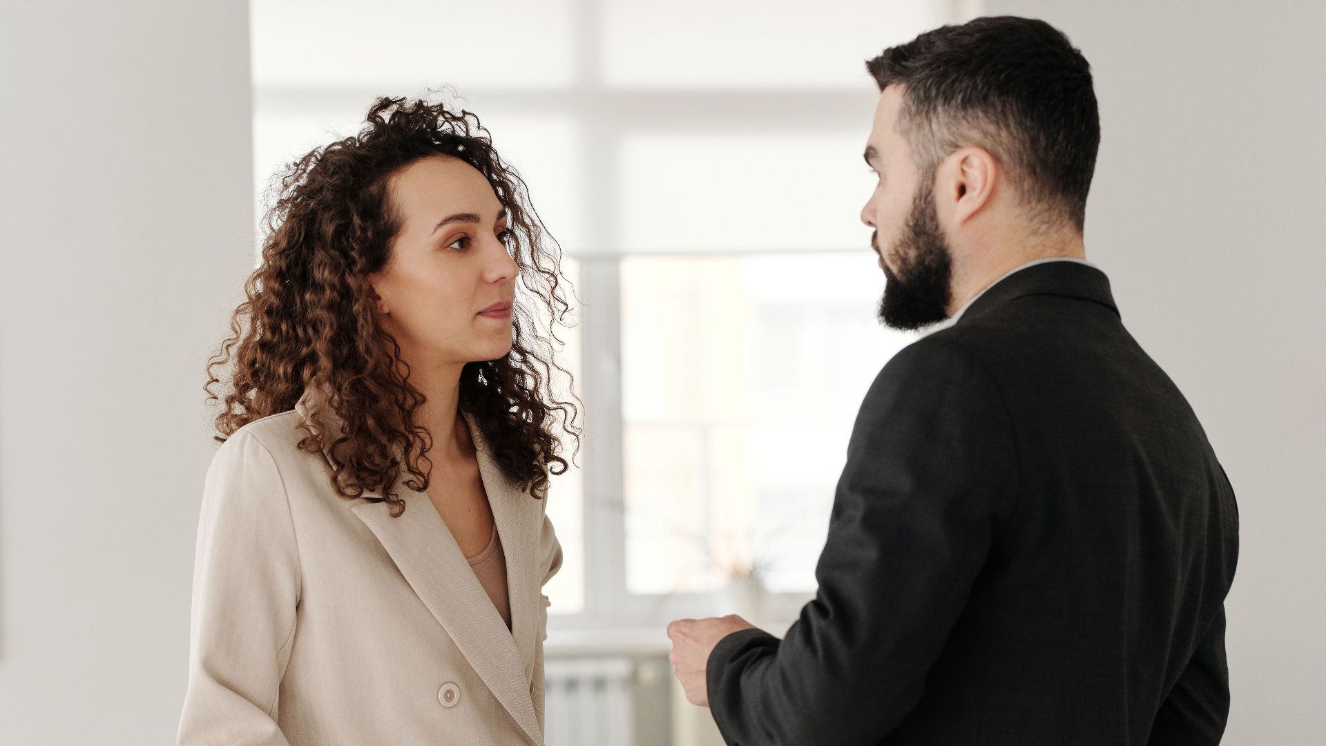 Two professionals engaged in a discussion in a bright, modern office setting.
