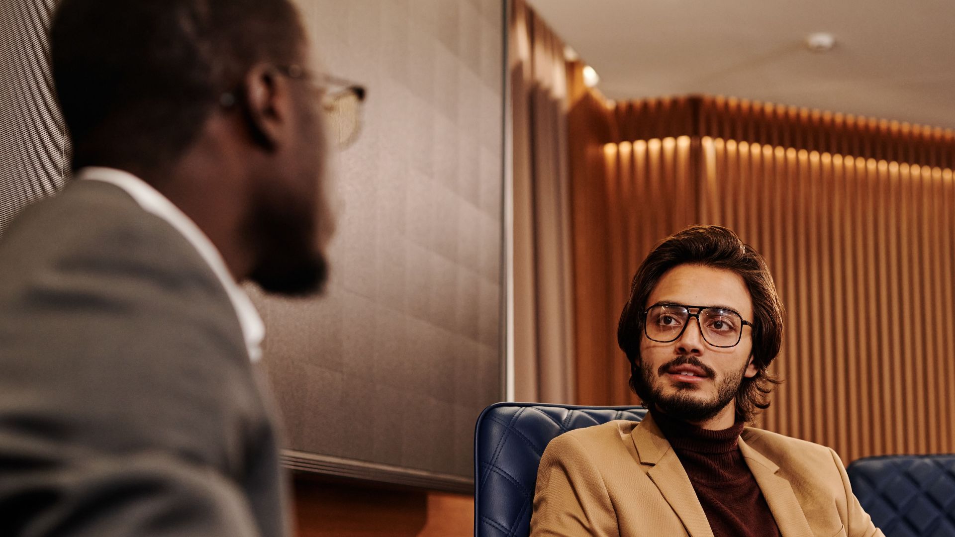 Two businessmen in a corporate setting engaged in discussion, fostering collaboration.